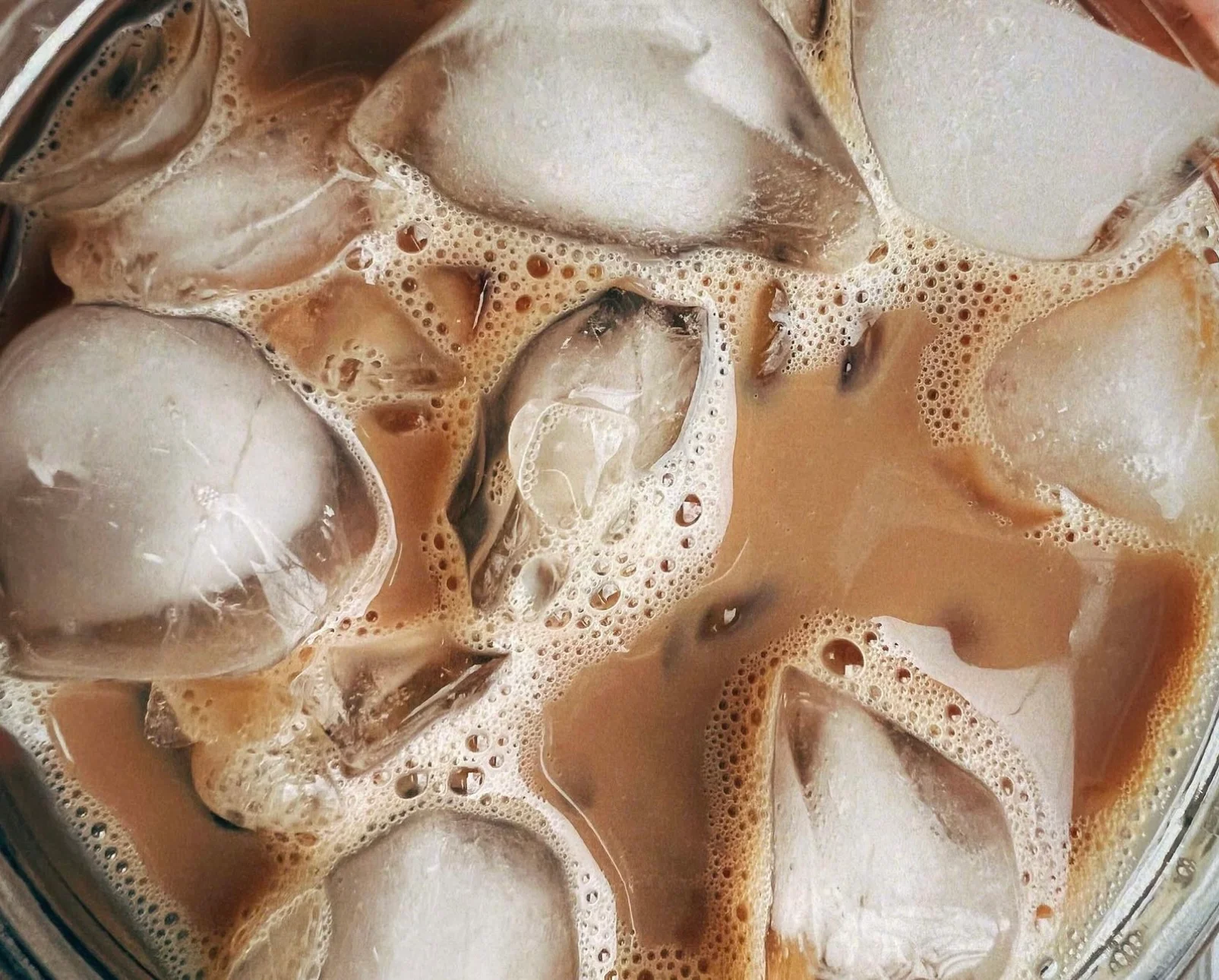 Iced coffee with ice cubes and frothy texture
