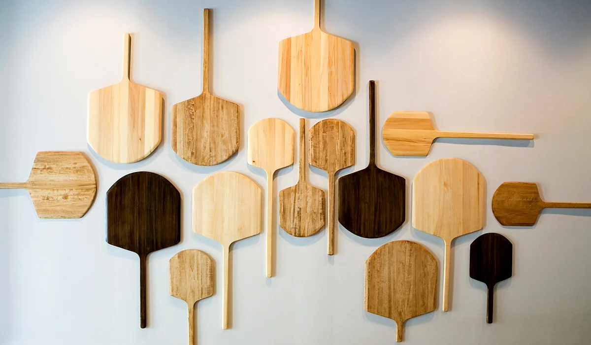 Artistic display of wooden pizza peels on a restaurant wall