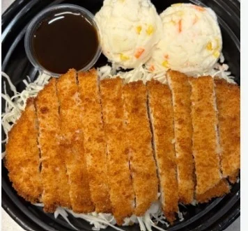 A plate featuring crispy breaded chicken cutlets, served with a side of coleslaw and a small container of dipping sauce.