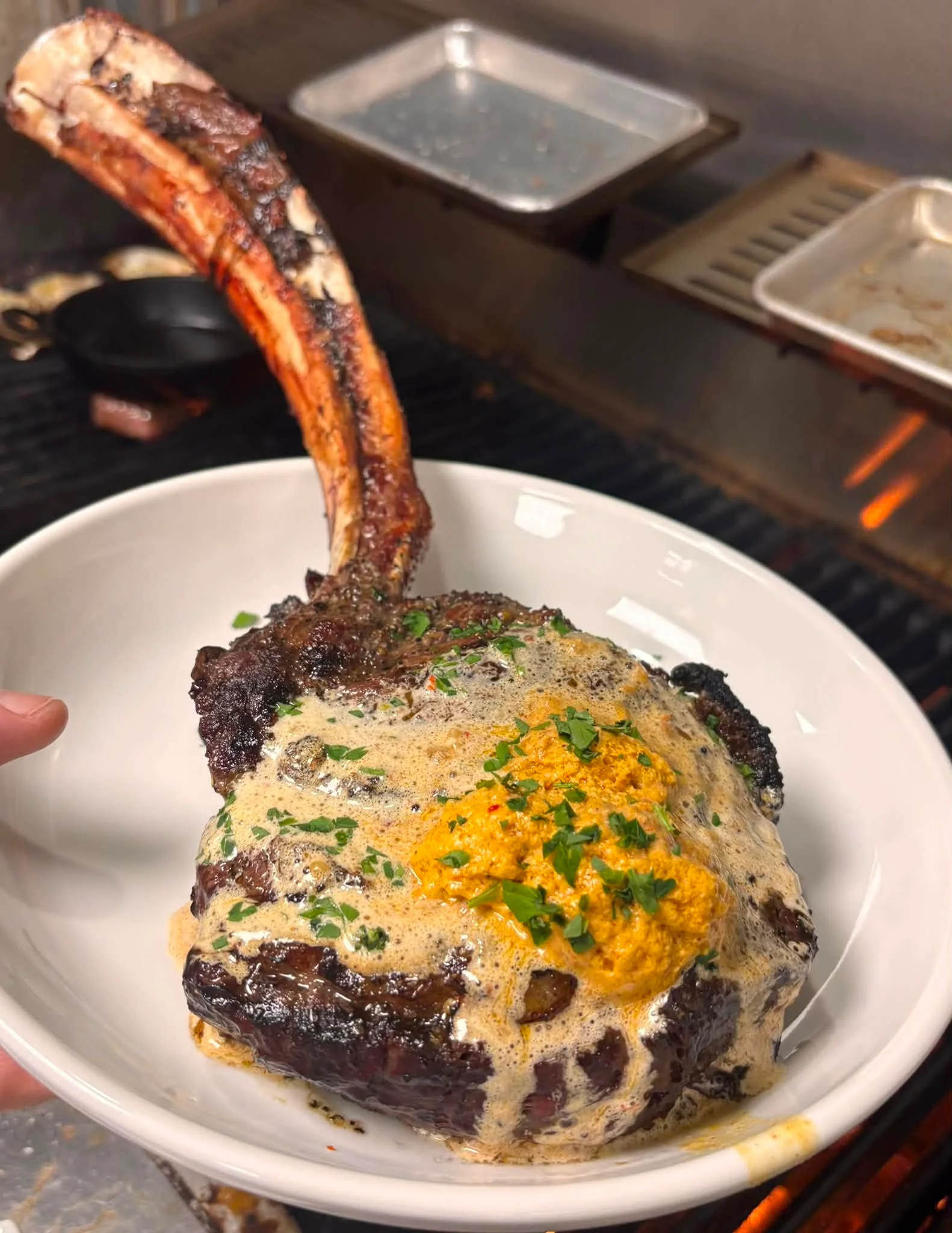 Grilled tomahawk steak with creamy sauce and herbs