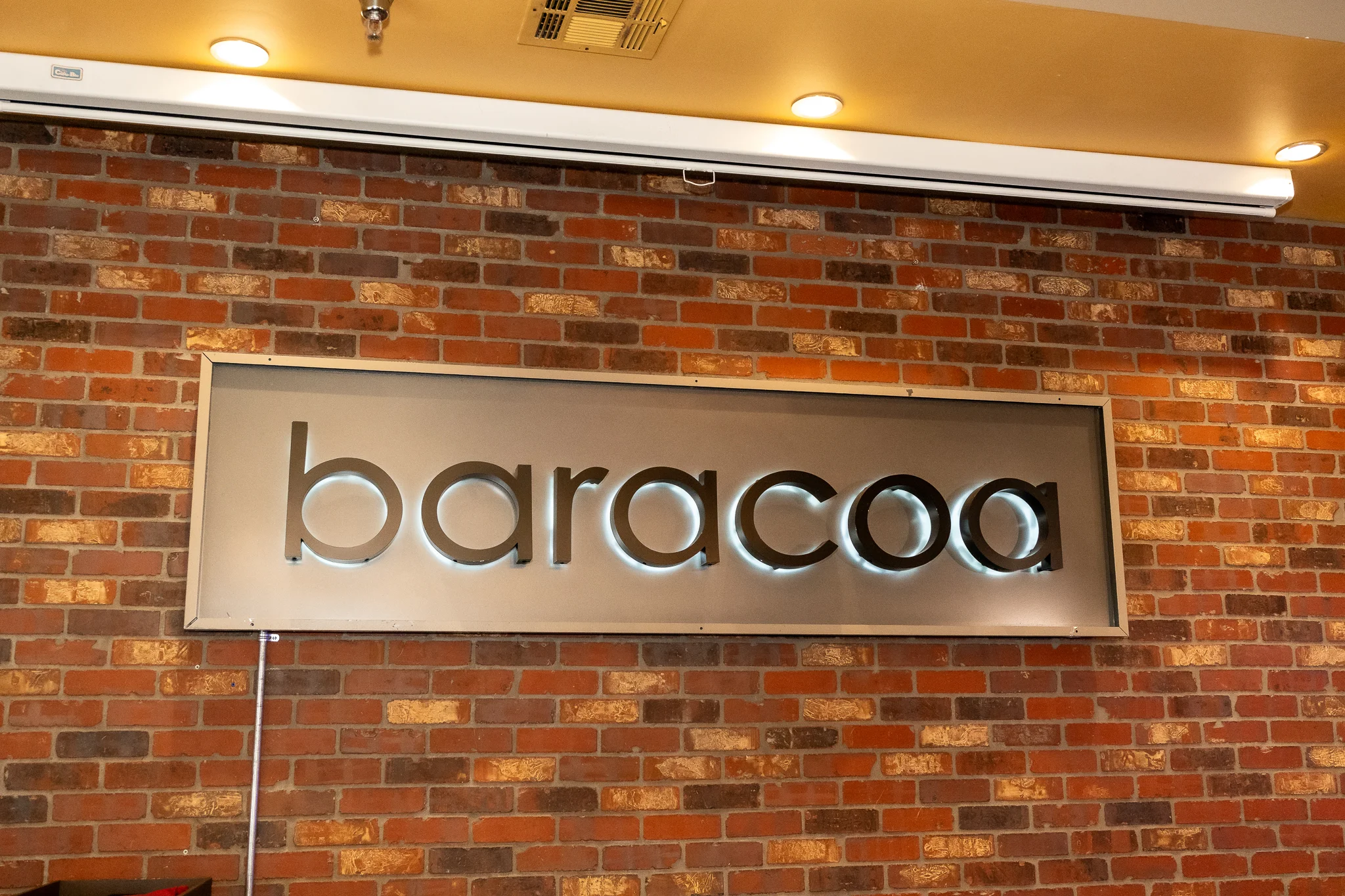 Restaurant sign for Baracoa with exposed brick background
