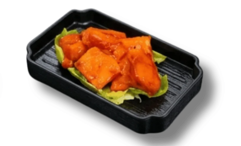 A serving of spicy orange glazed potatoes on a bed of lettuce in a black tray.