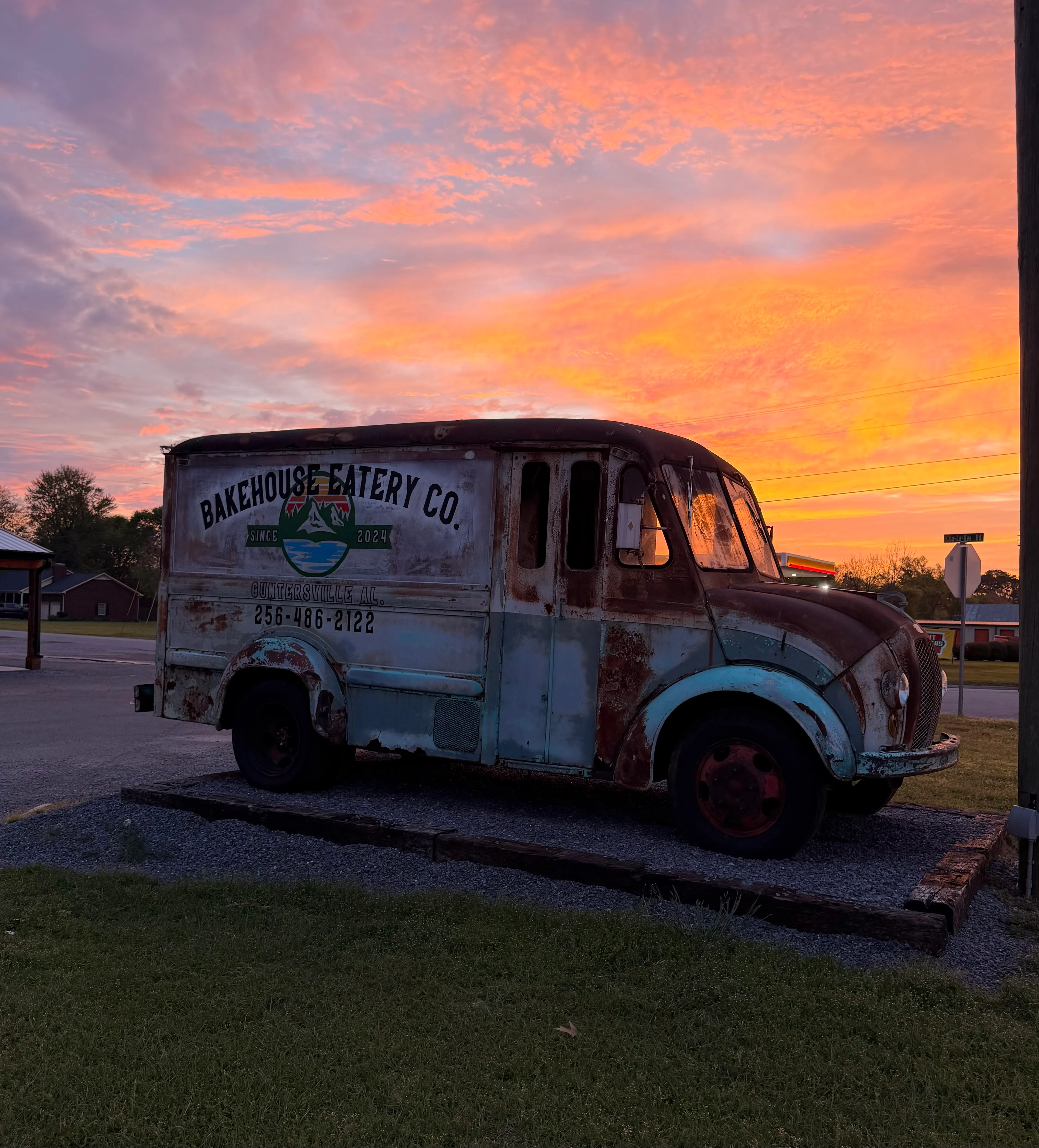 Vintage bakery trailer beneath a vivid pink and orange sunset sky