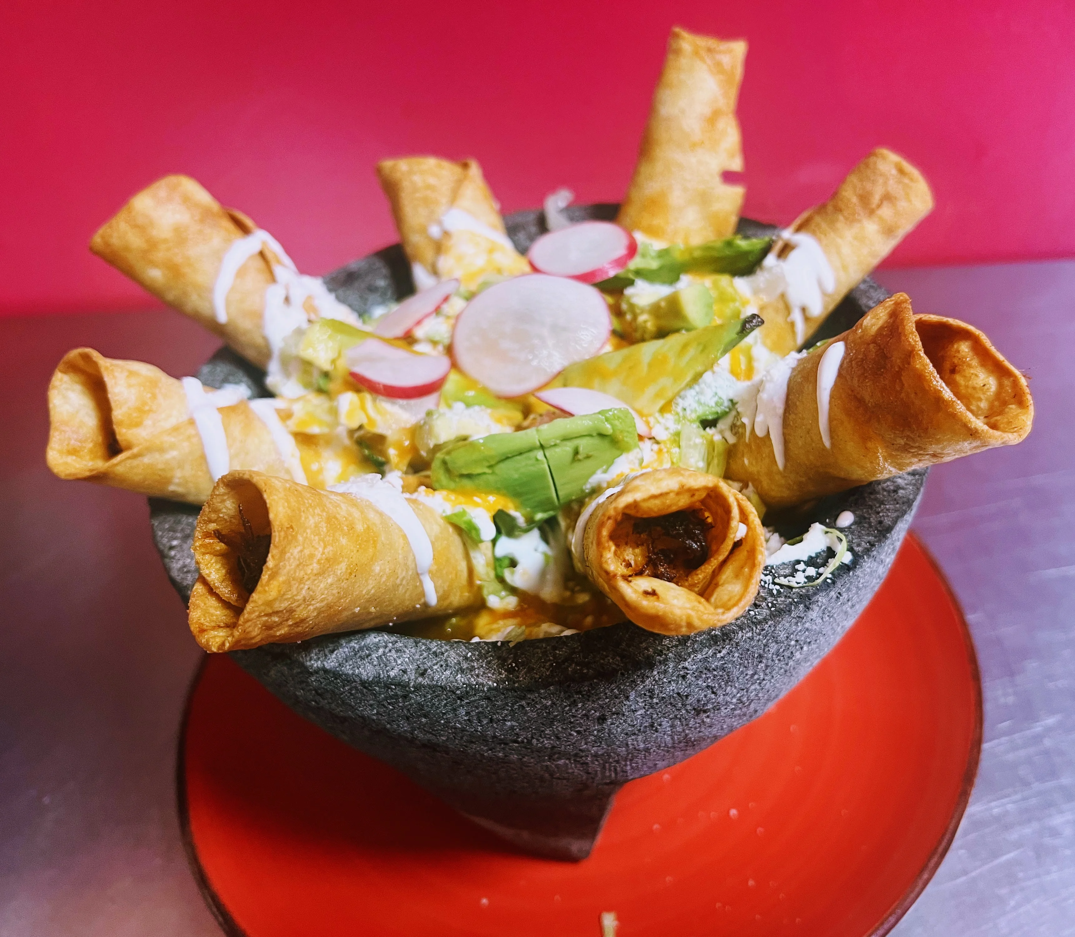 Crispy Mexican flautas served in a traditional stone bowl