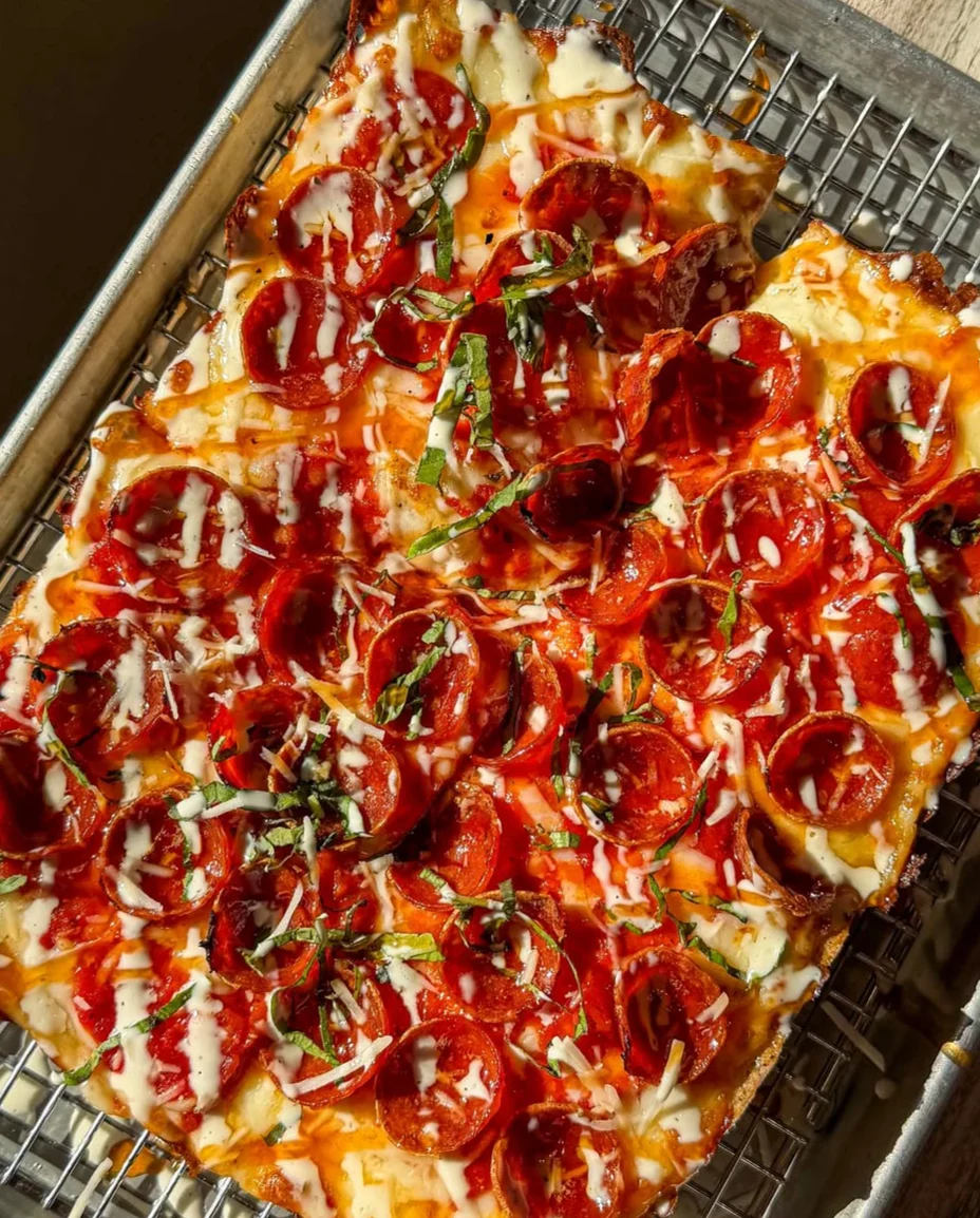 Delicious pepperoni pizza with fresh basil and drizzled sauce