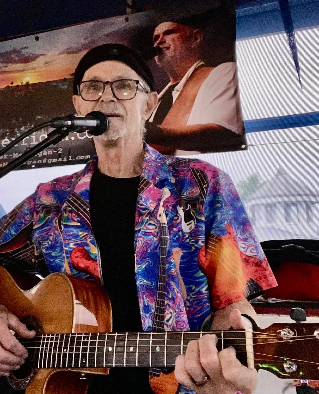 Musician performing live with guitar in vibrant shirt