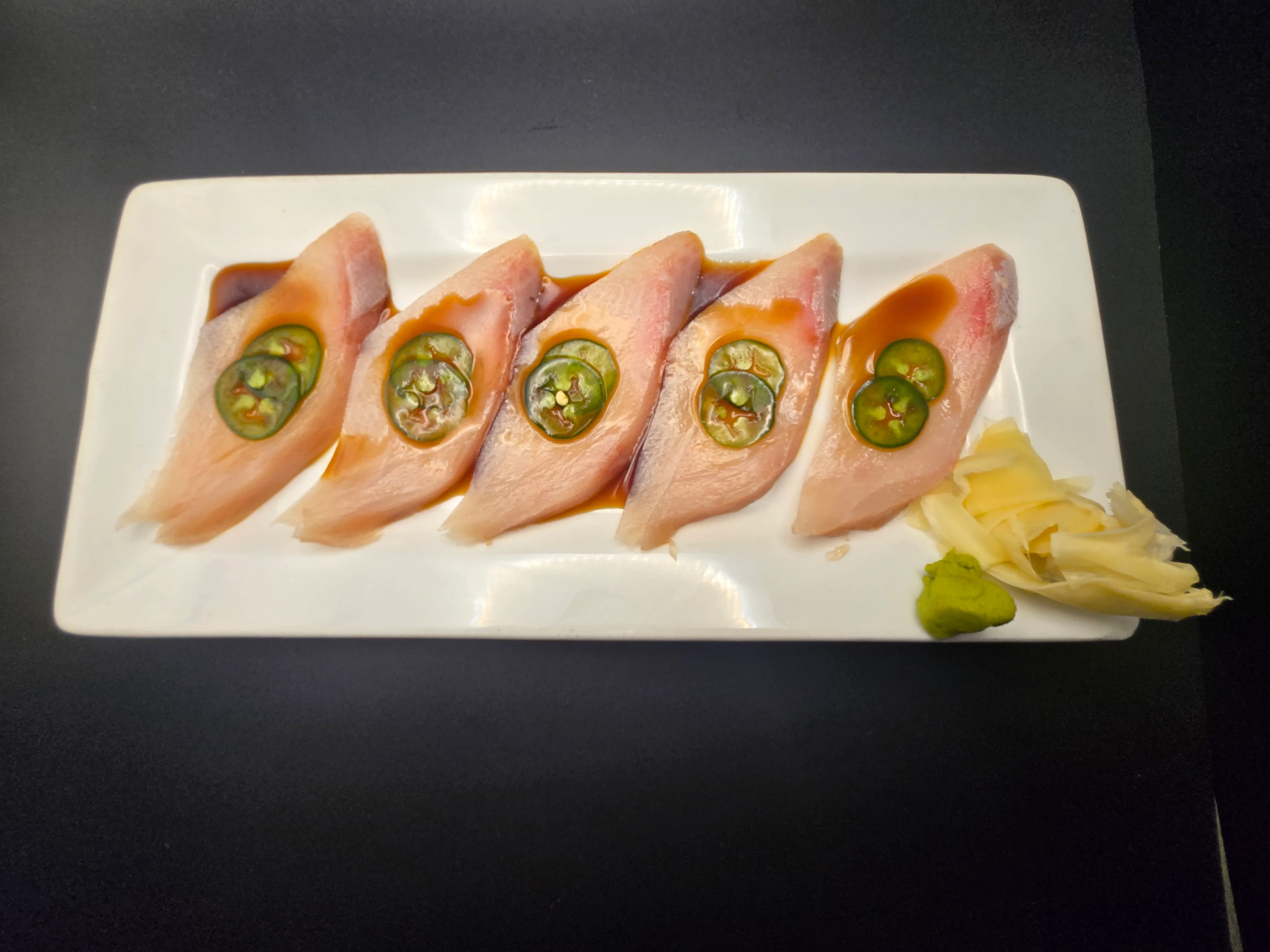Japanese sashimi with jalapeño slices and soy sauce