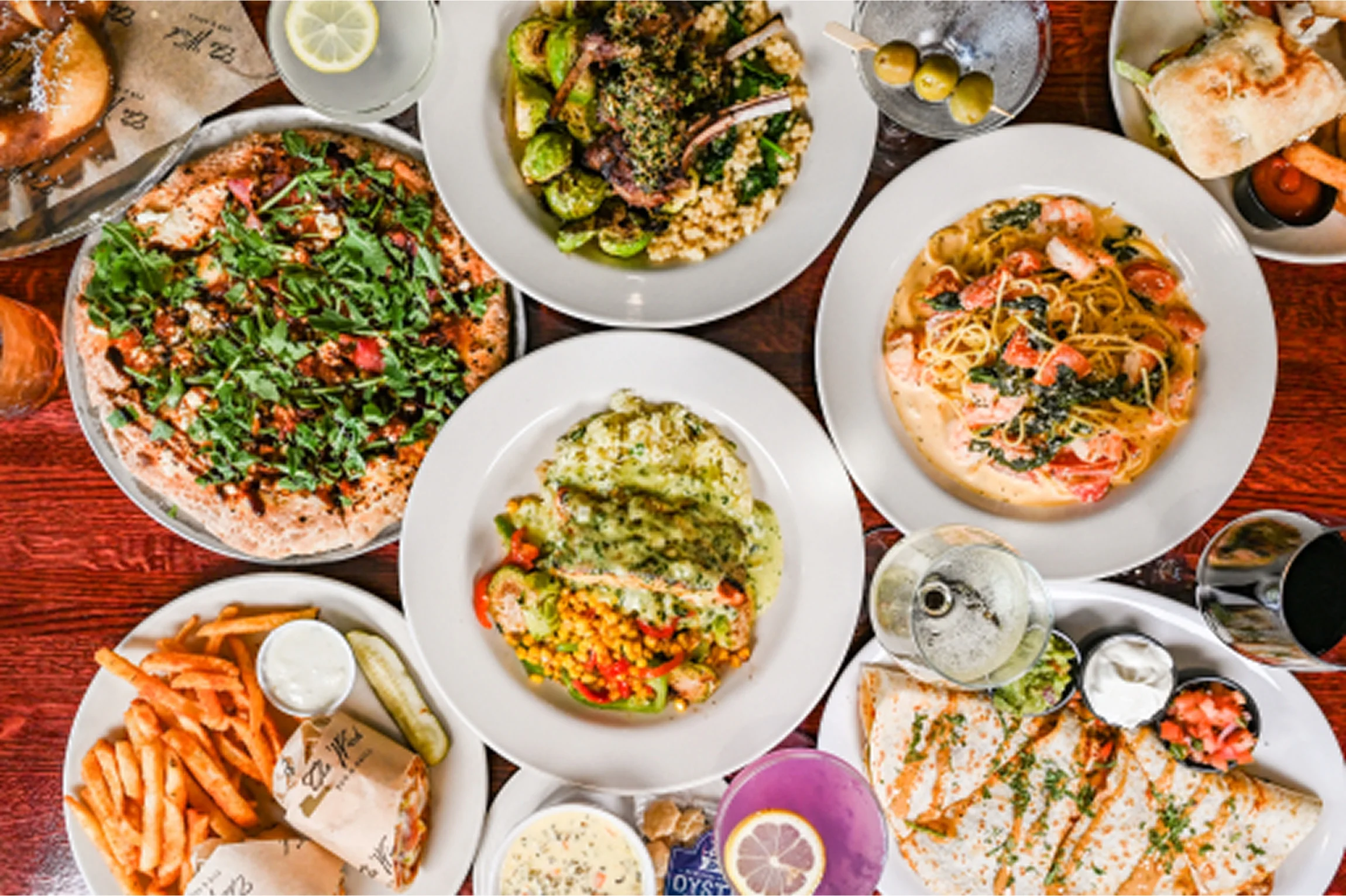 Assorted dishes including pizza, pasta, and seafood in a vibrant restaurant setting