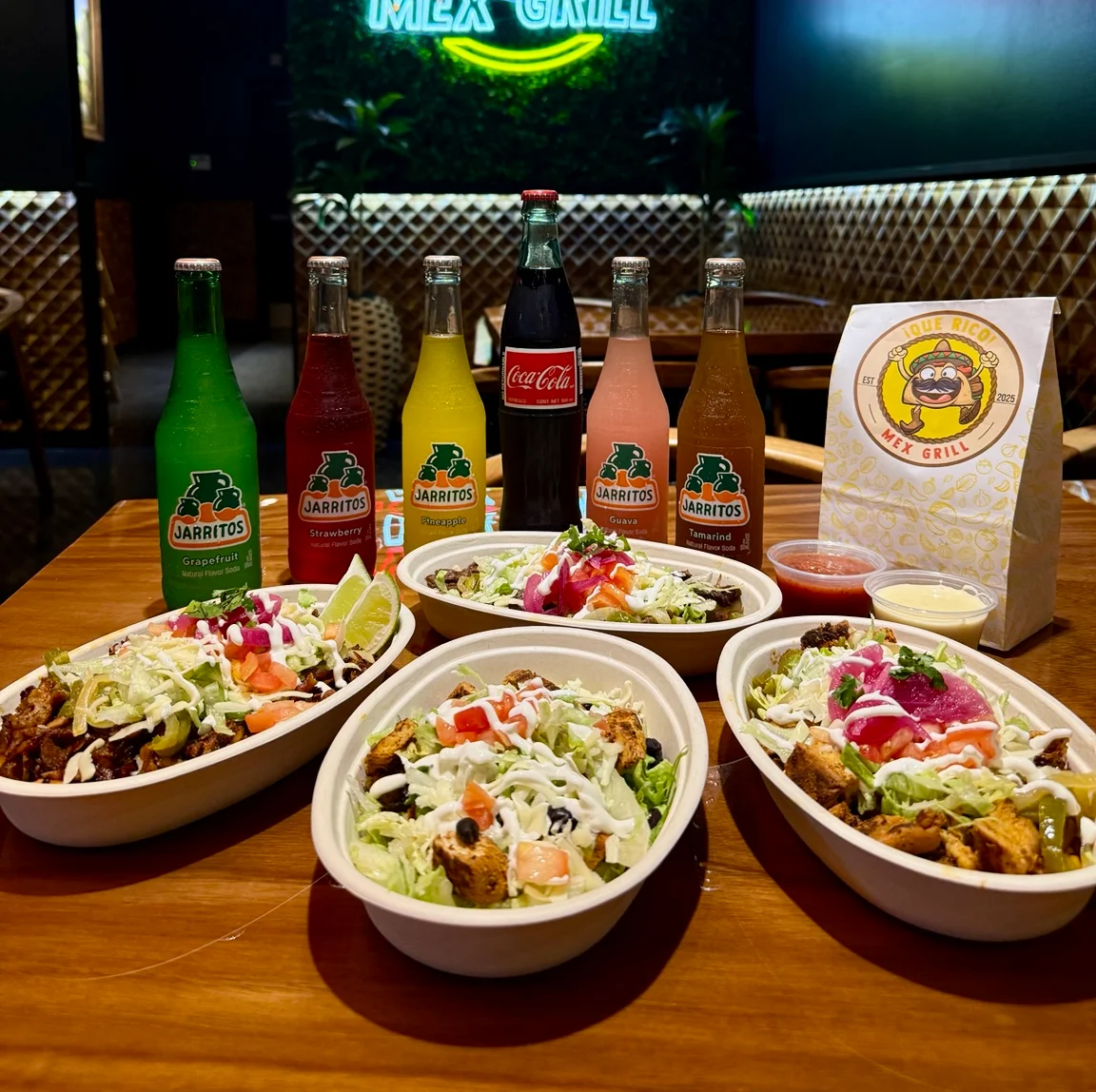 Colorful Mexican bowls with fresh toppings and drinks in a vibrant restaurant setting