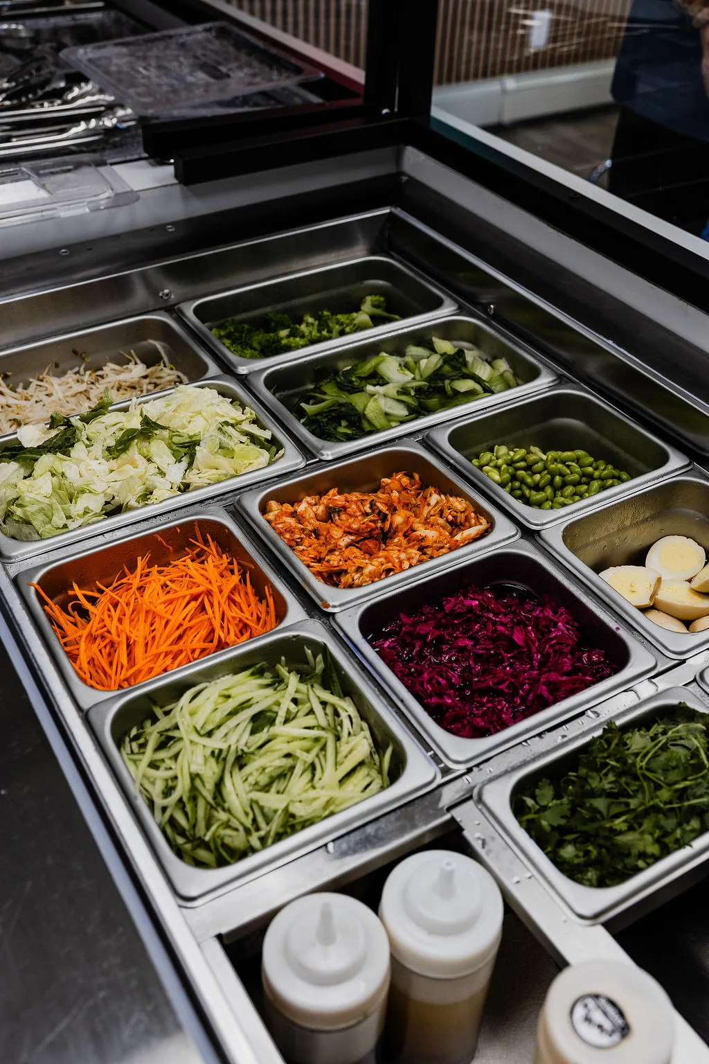 an array of fresh toppings in a cold hold table