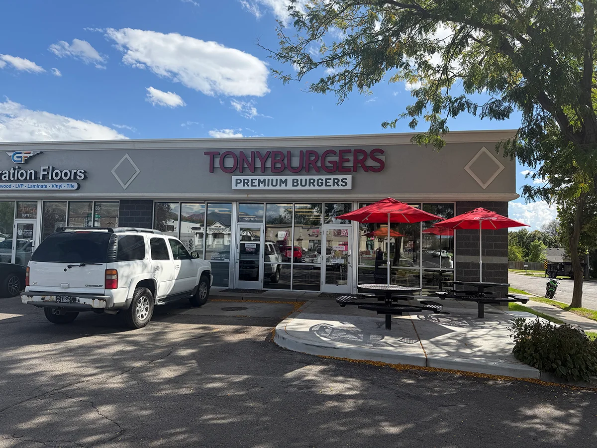 TonyBurgers restaurant storefront with outdoor picnic tables and red umbrellas