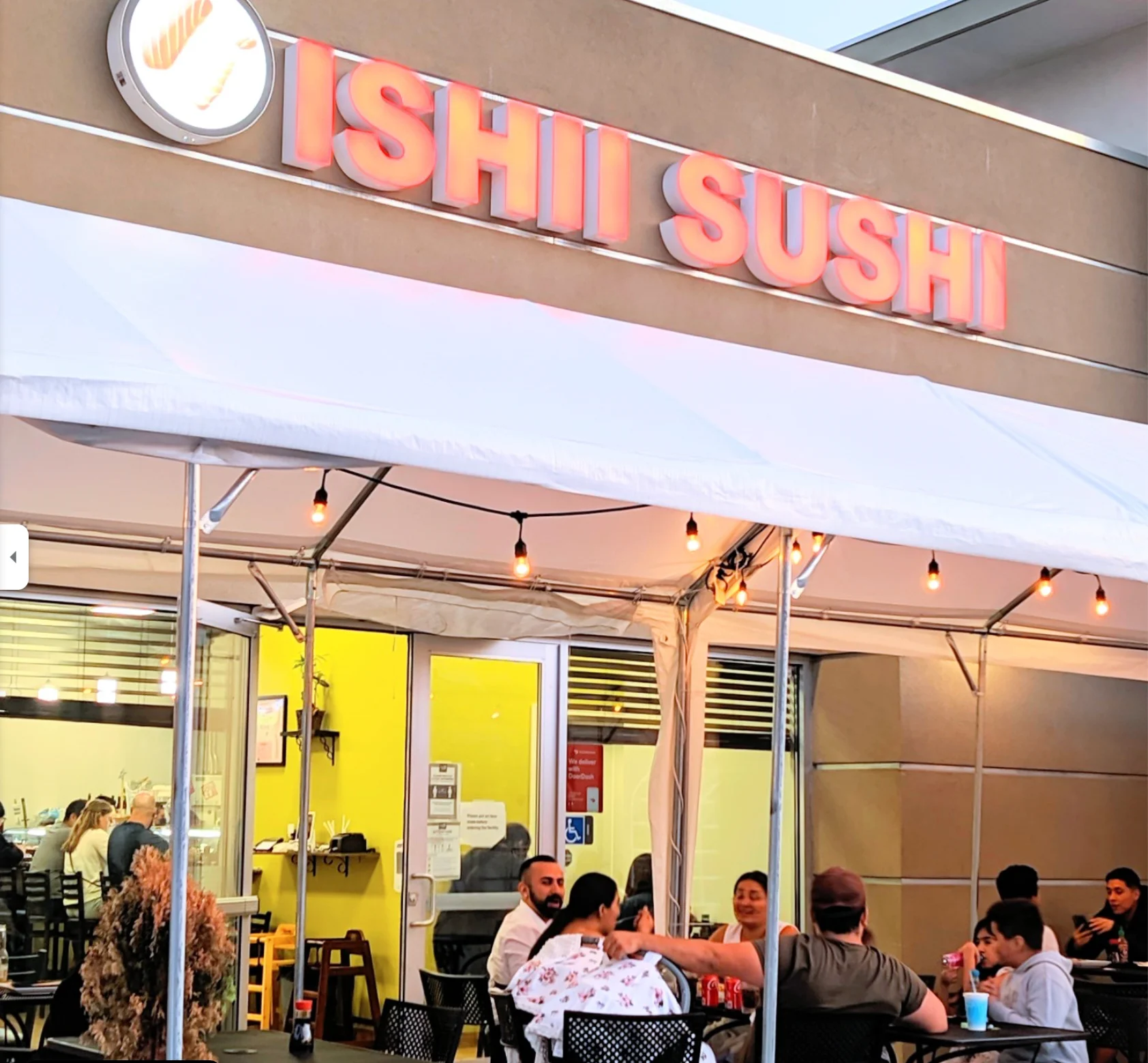Exterior of Ishi Sushi restaurant with outdoor seating and warm lighting