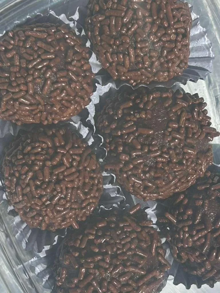 A selection of chocolate truffles coated with chocolate sprinkles, arranged in small paper cups.
