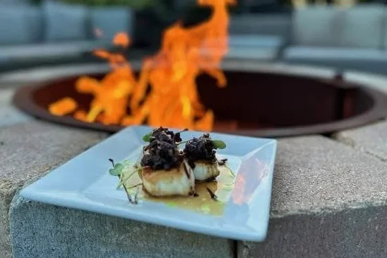 Seared scallops with black garlic sauce by a fire pit