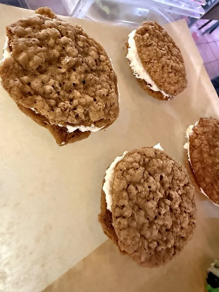 A collection of oatmeal cream pies on a tray, showcasing their chewy texture and creamy filling between two cookies.