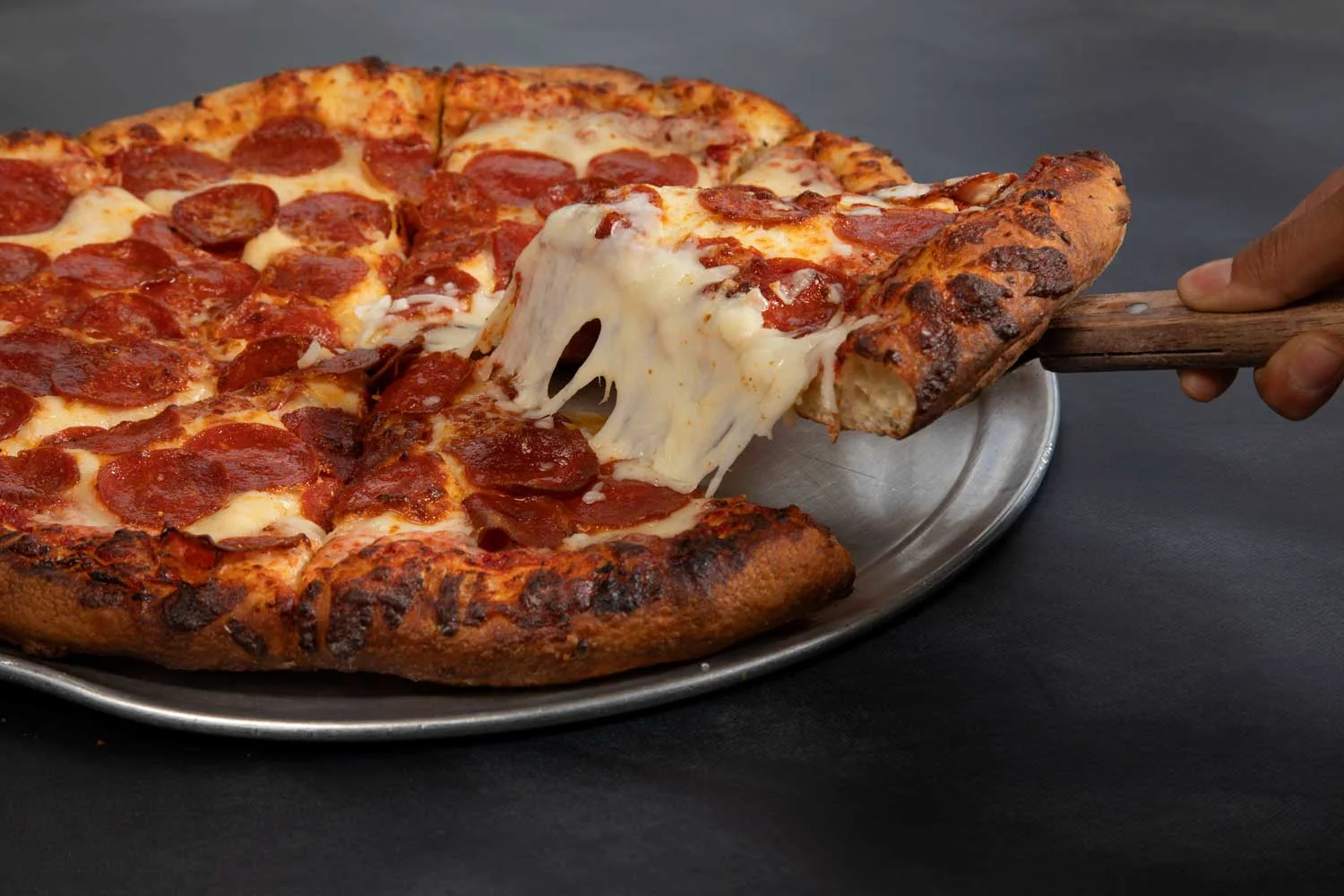 Delicious pepperoni pizza with gooey cheese on a metal serving tray