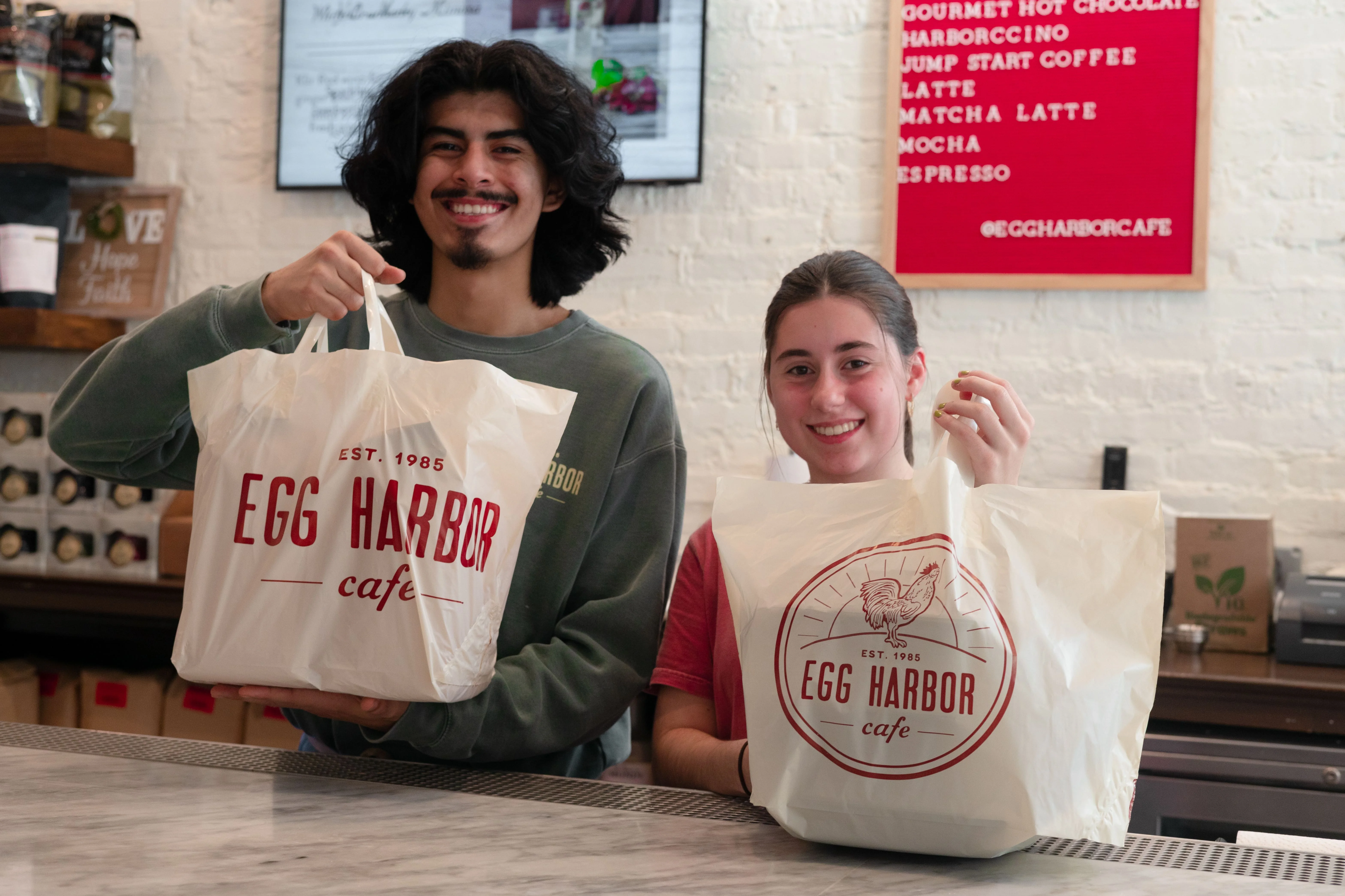Happy customers holding takeout bags from Egg Harbor Cafe