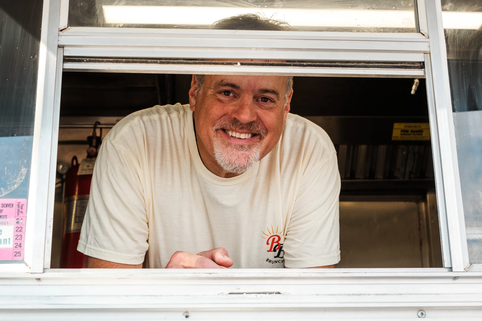 Friendly food truck operator smiling from window