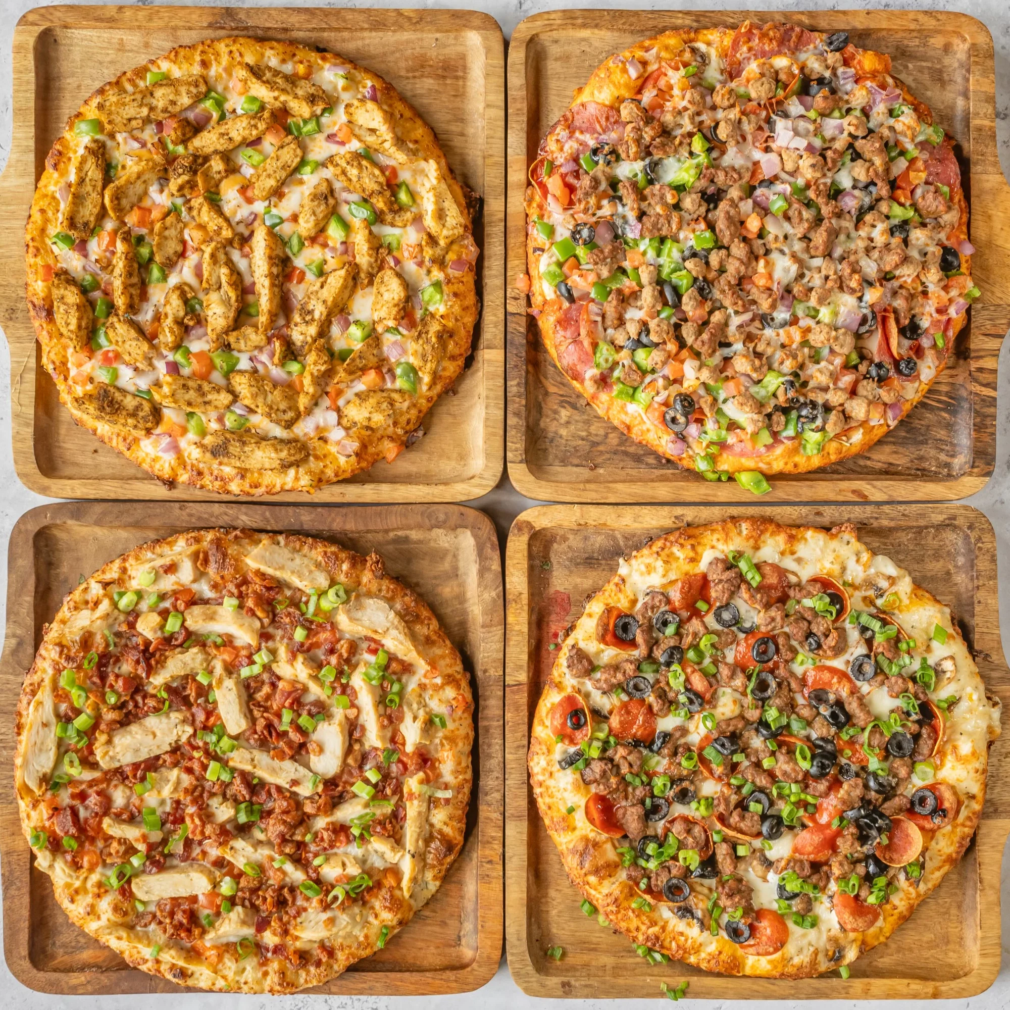 Four gourmet pizzas on wooden boards, showcasing diverse toppings