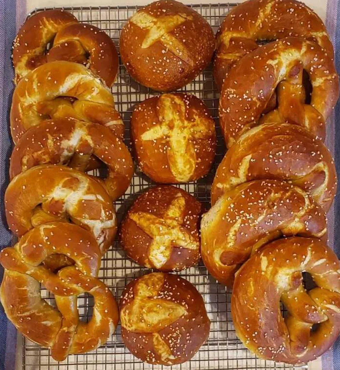 Freshly baked pretzels and rolls on a cooling rack.