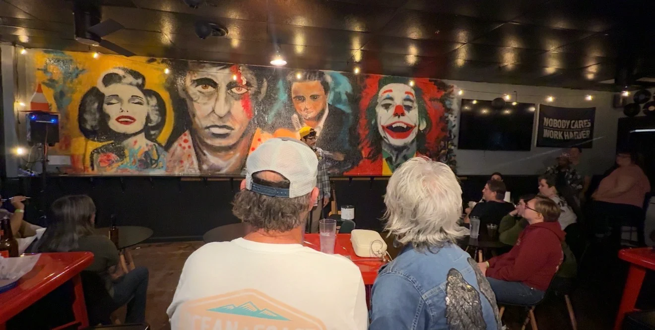Vibrant restaurant interior with colorful mural and audience enjoying live performance