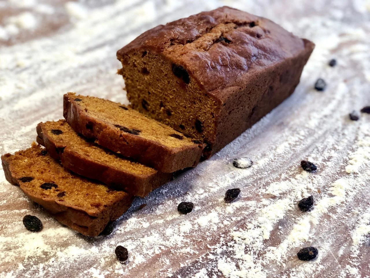 Sliced pumpkin bread with raisins on a floured surface