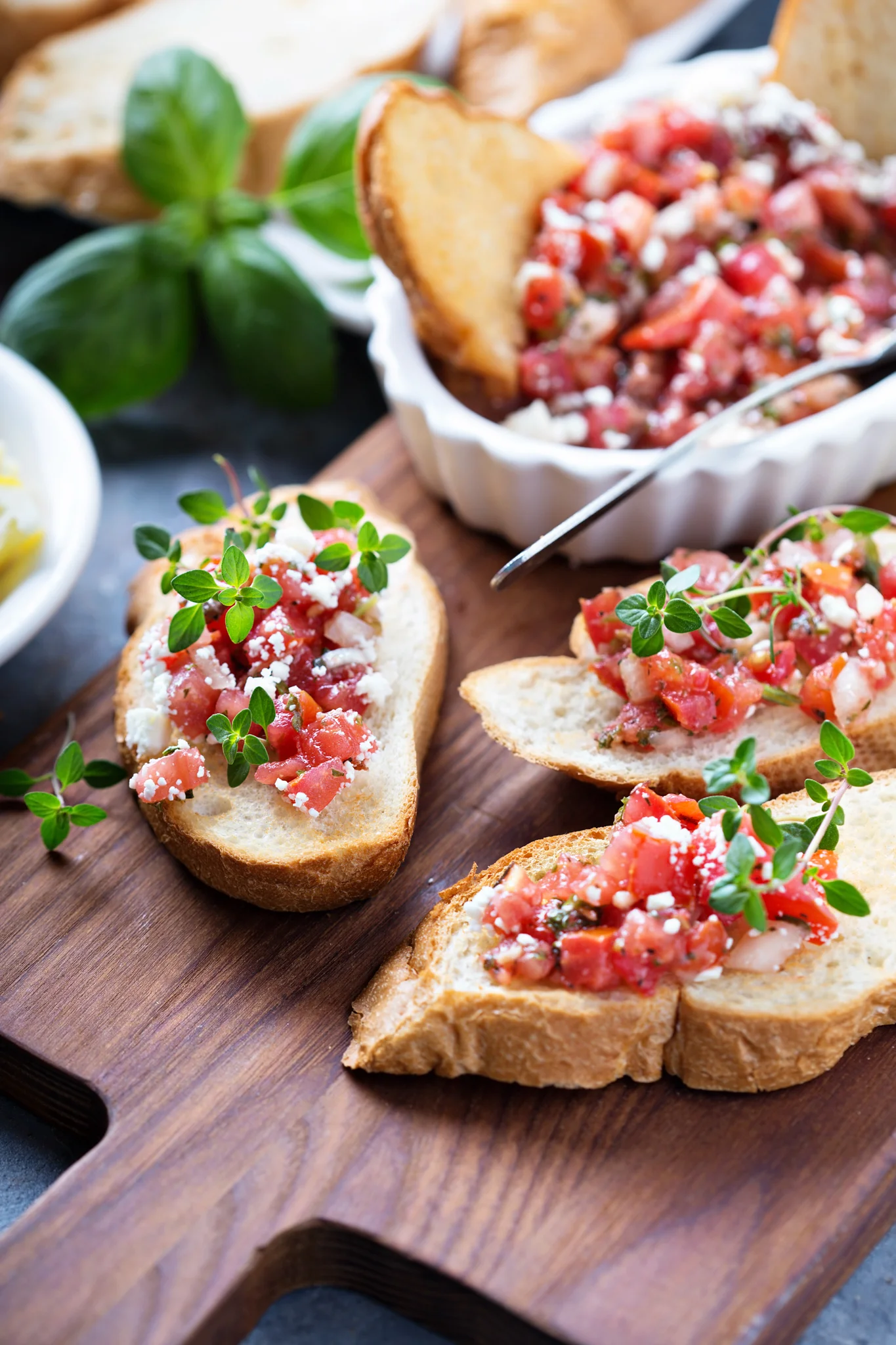 Bruschetta topped with tomatoes and herbs on a wooden board.