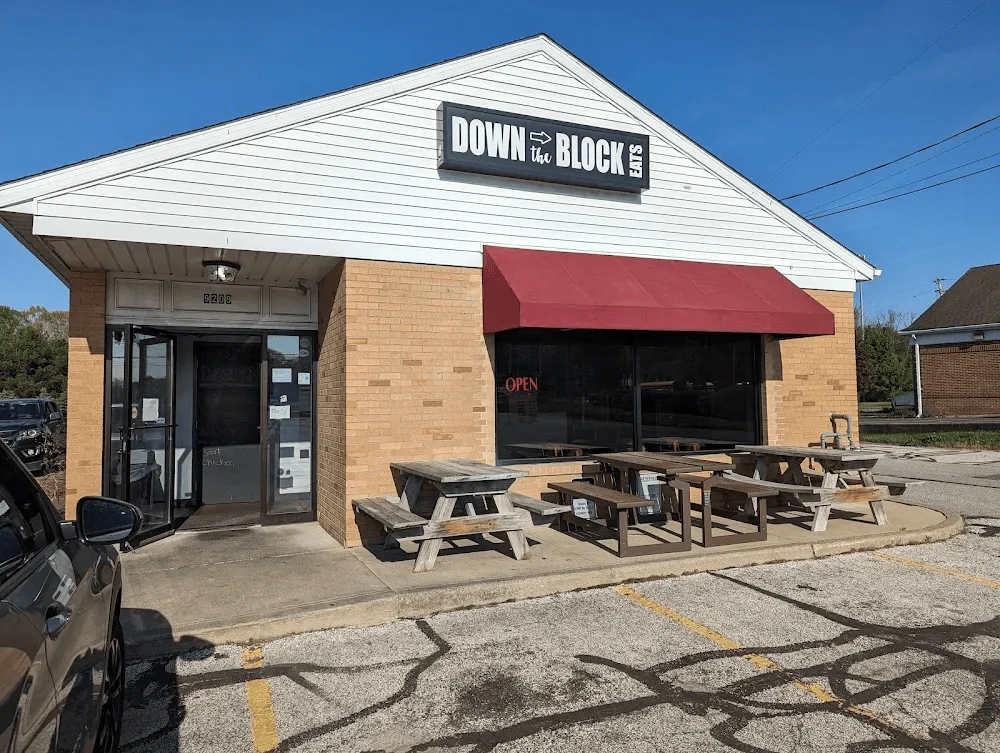 The exterior of a dining establishment with picnic-style tables and a welcoming 'OPEN' sign.