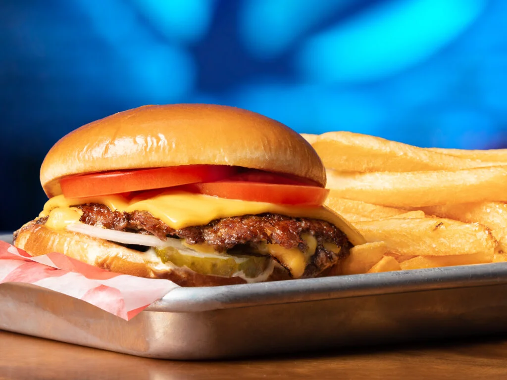 Juicy cheeseburger with fries on a metal tray