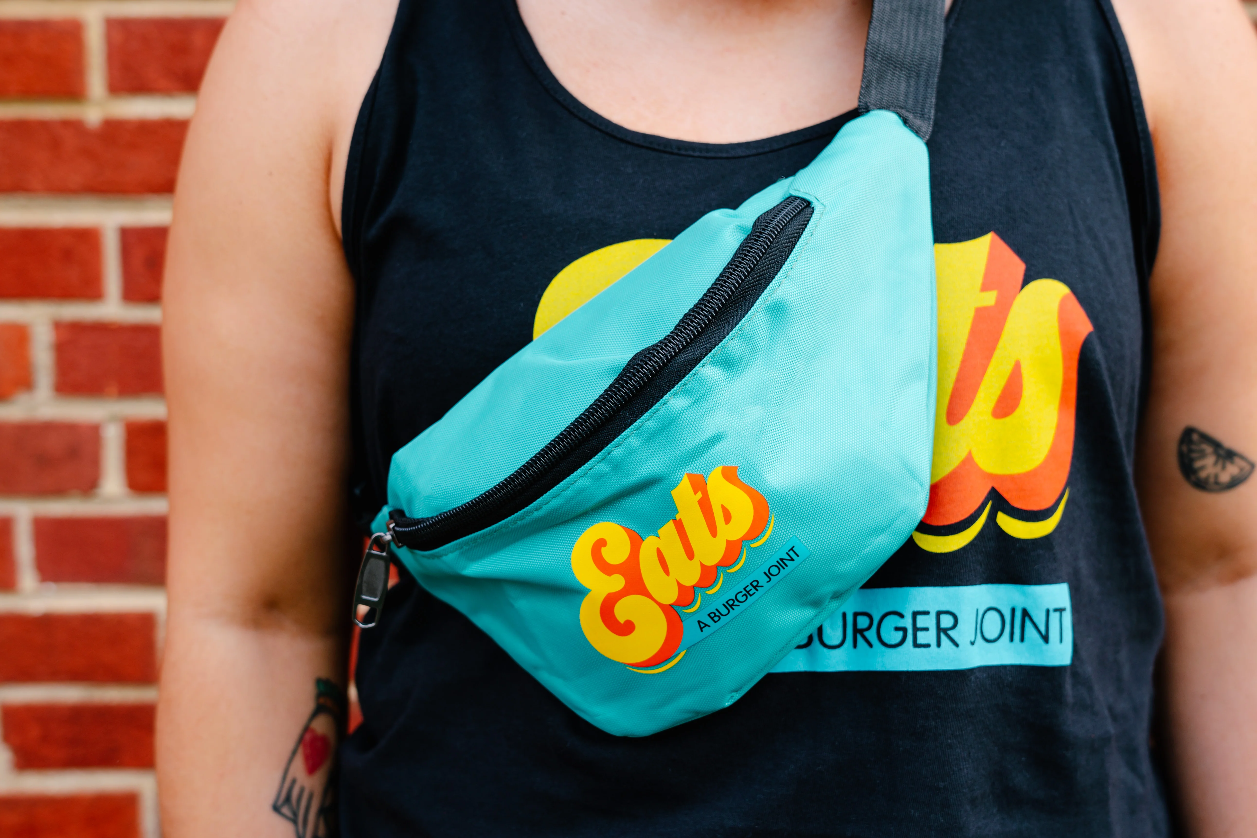 Person wearing a tank top and fanny pack from a burger joint