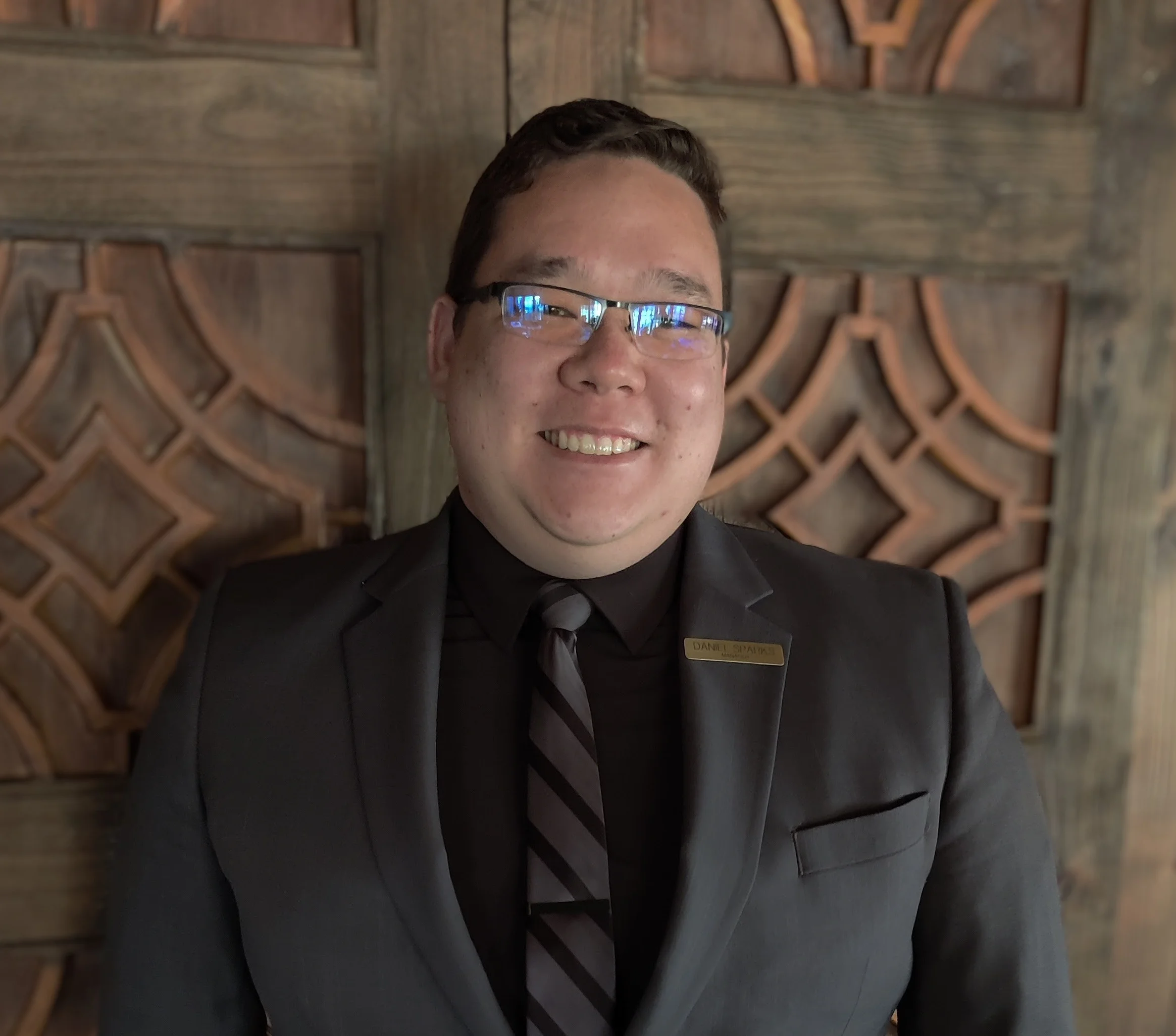 Professional man in a suit posing against a wooden backdrop