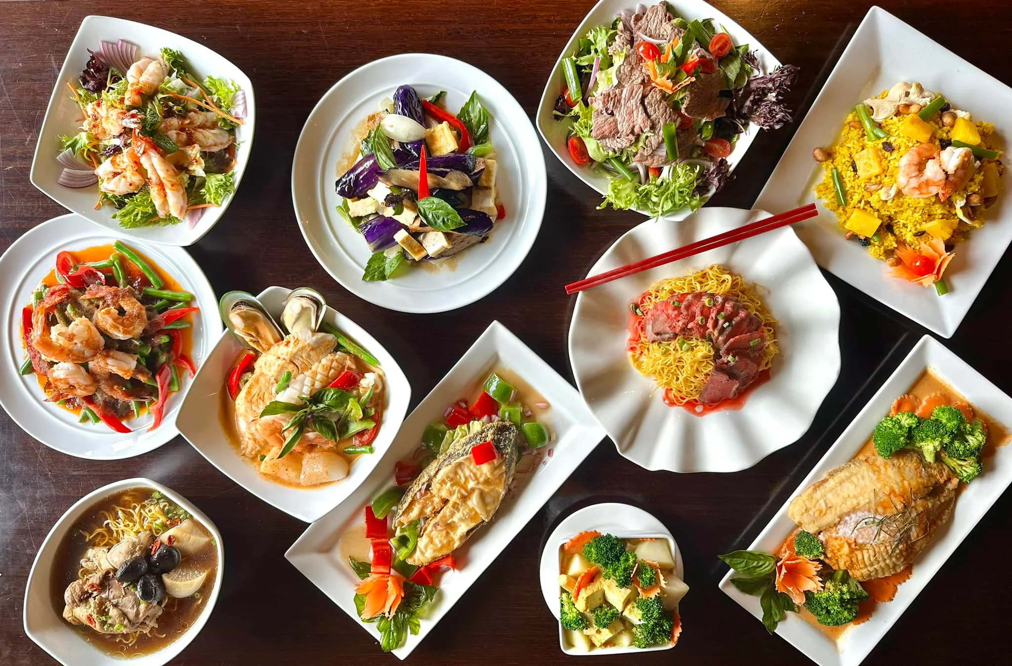 Assorted Asian seafood and vegetable dishes on a wooden table