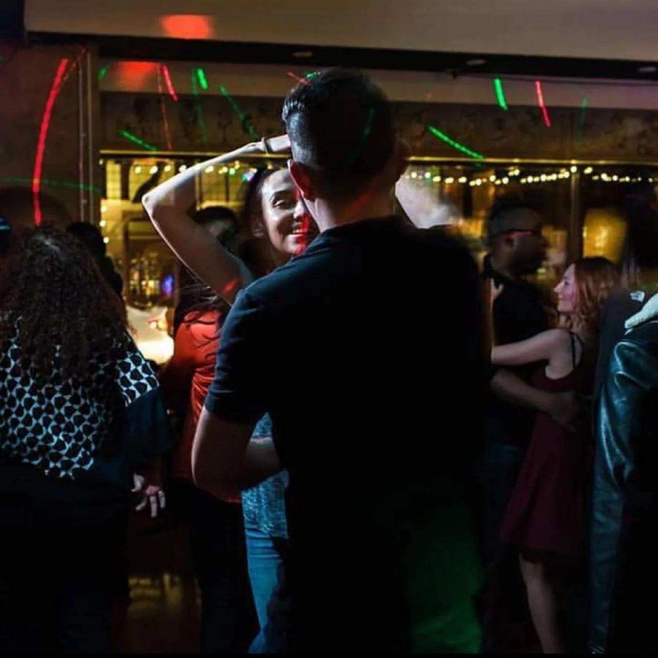 Couple dancing on a vibrant dance floor with colorful lights at a Mexican restaurant.