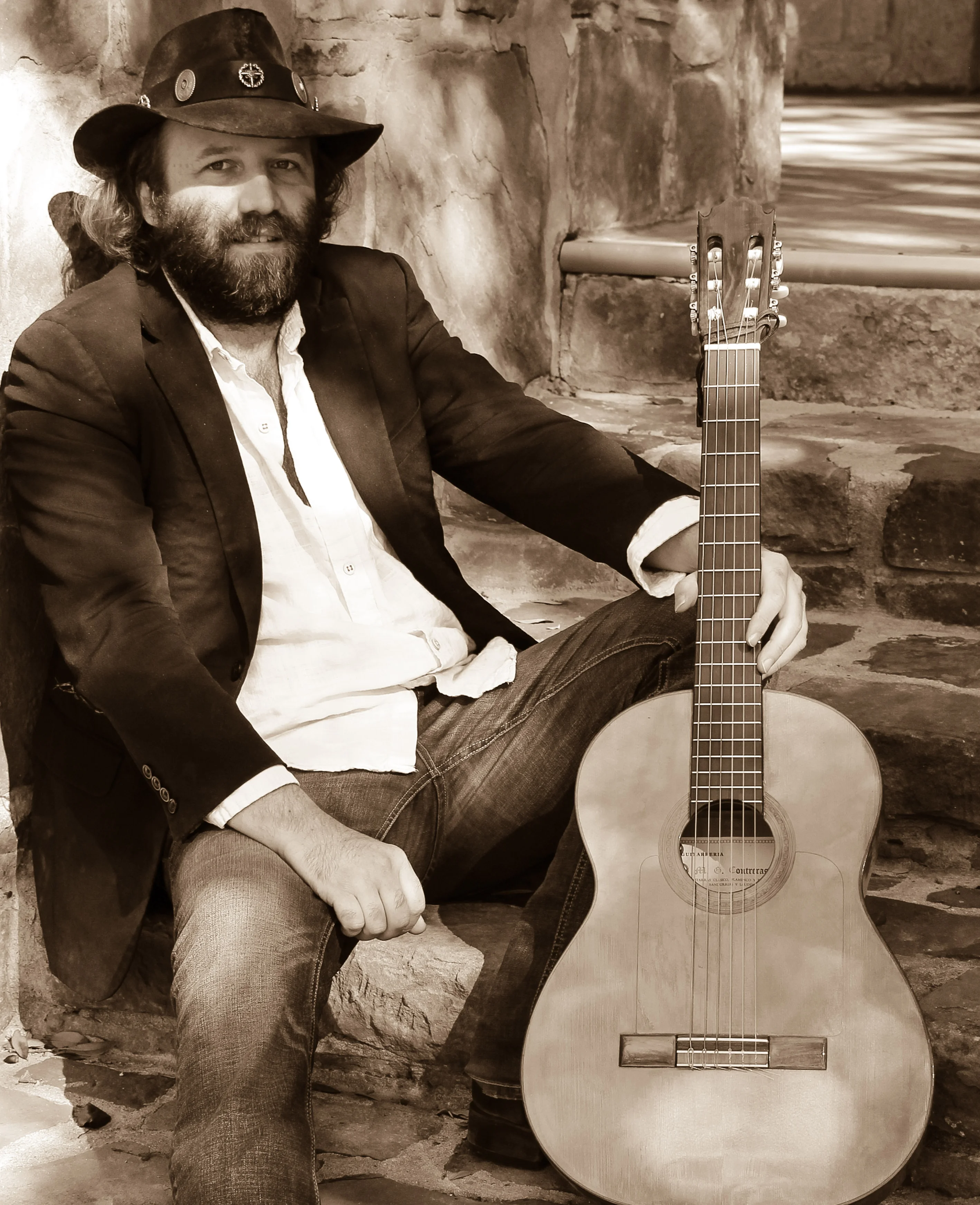 Musician seated with guitar in a rustic outdoor setting