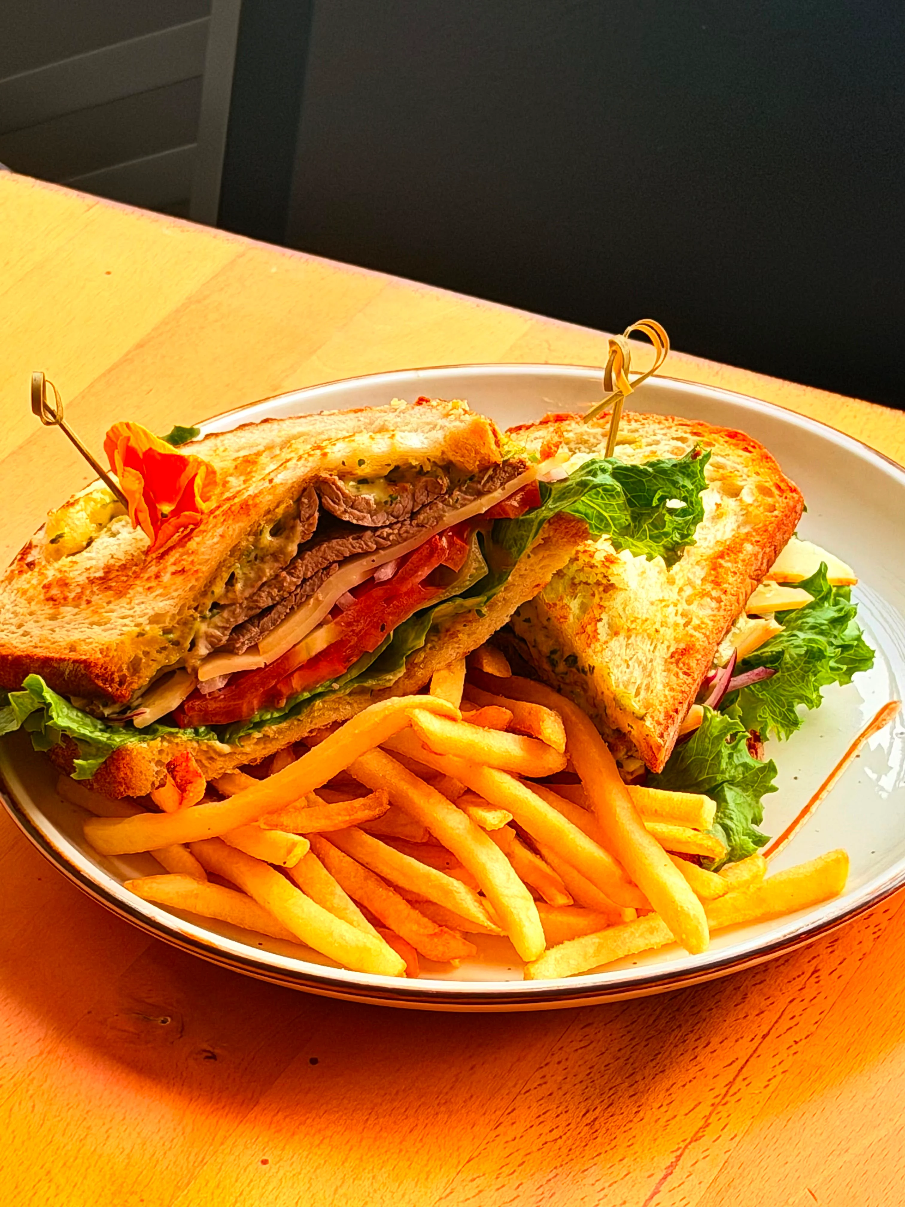 A hearty sandwich filled with layers of roast beef, lettuce, tomato, and onions, served with a side of golden French fries.