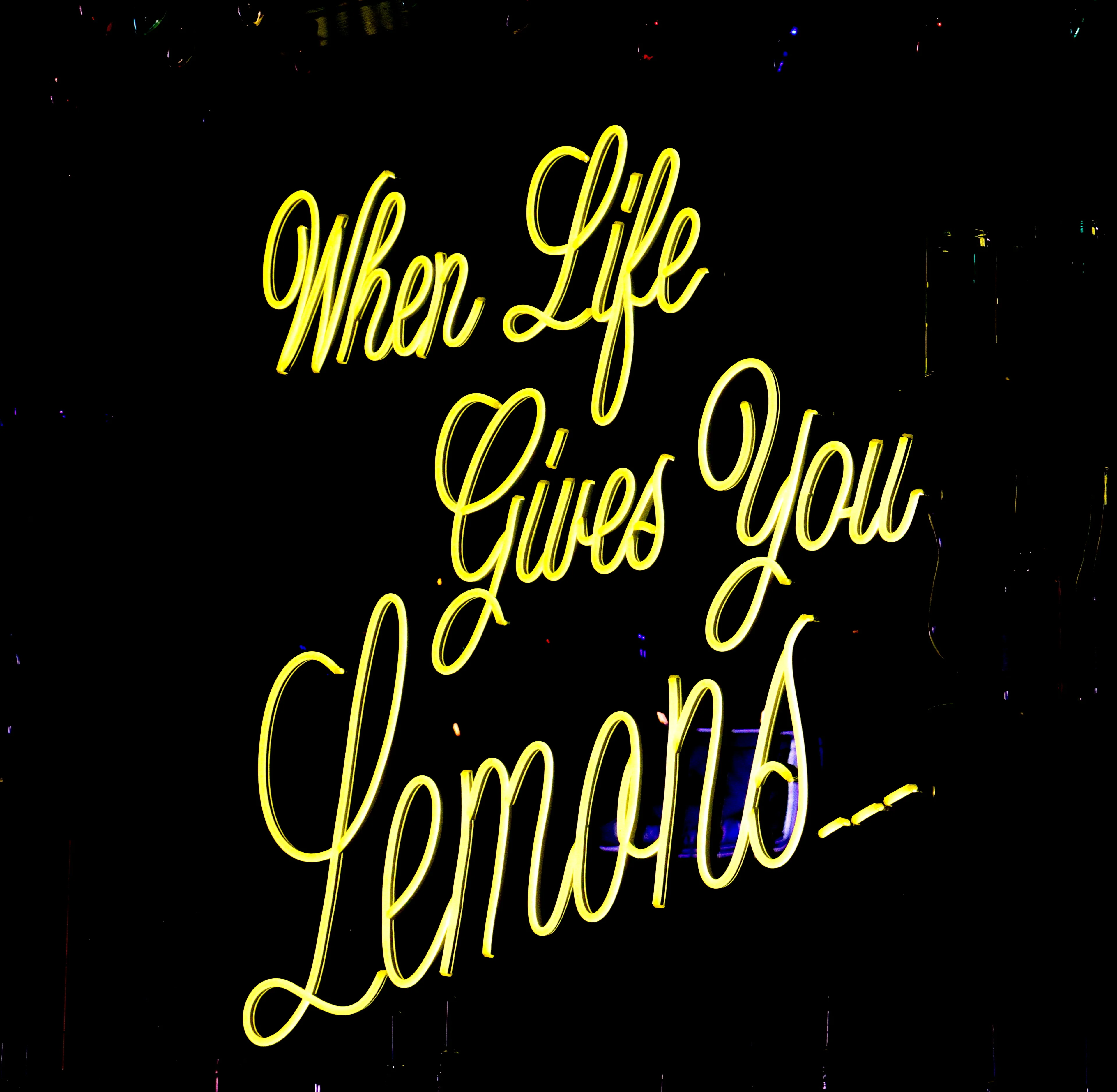 Neon sign reading 'When Life Gives You Lemons' in bright yellow