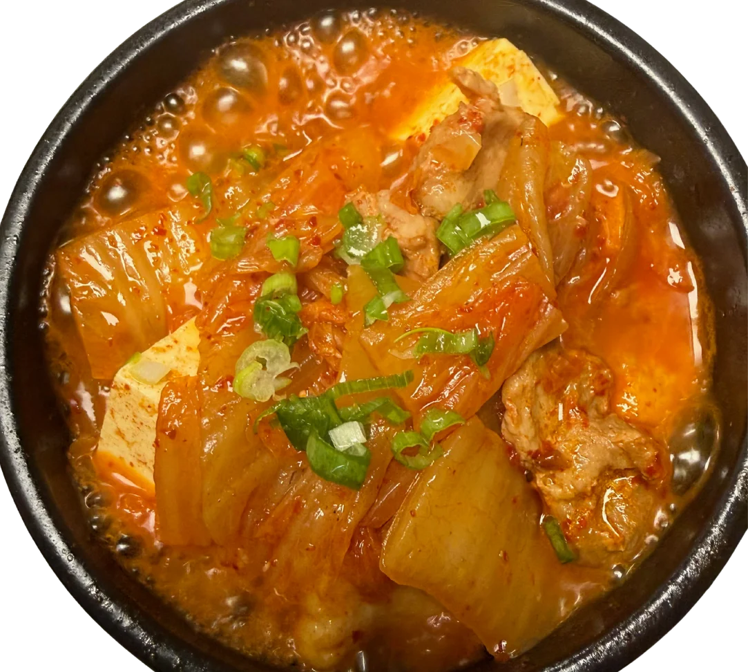 A steaming bowl of kimchi stew with tofu and green onions.