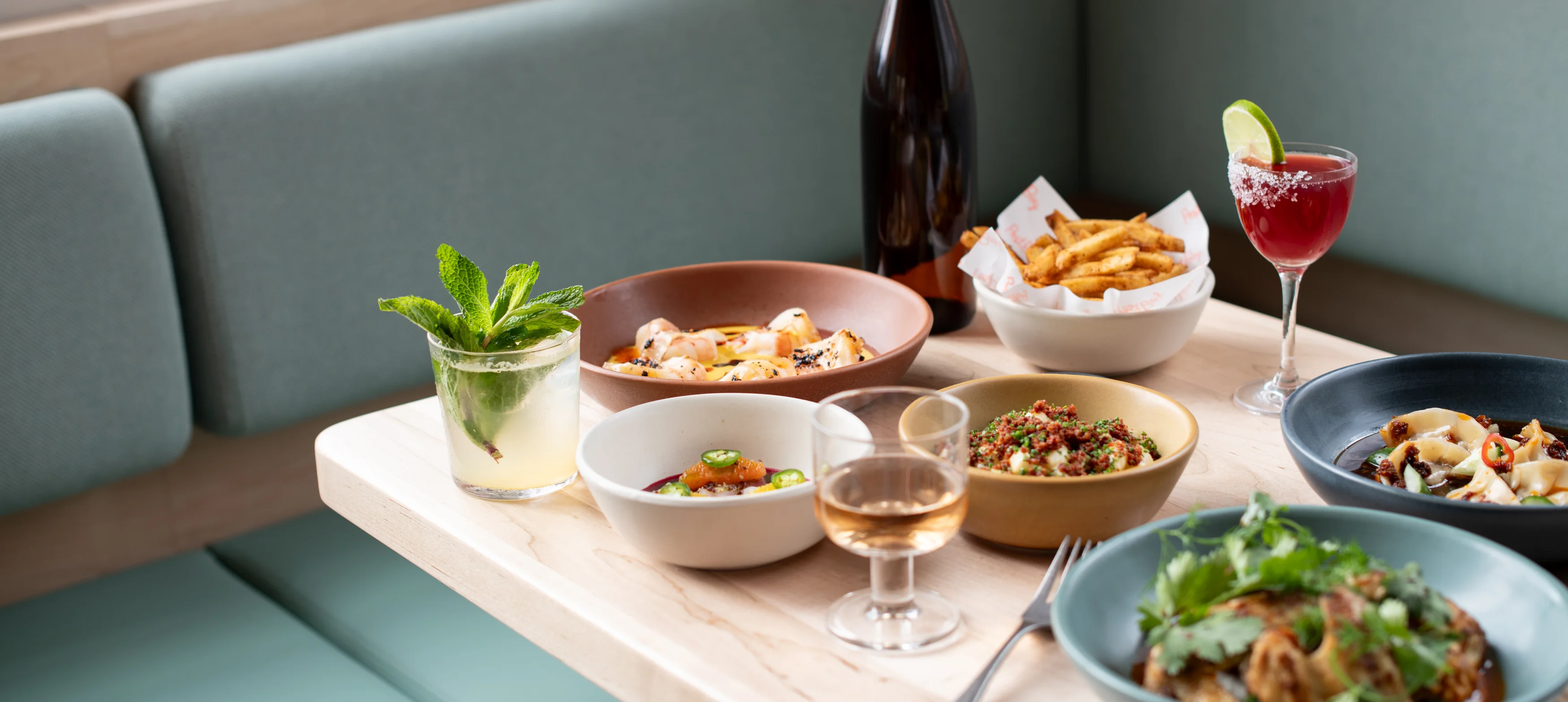 Assorted dishes including Mediterranean mezze and cocktails on a wooden table