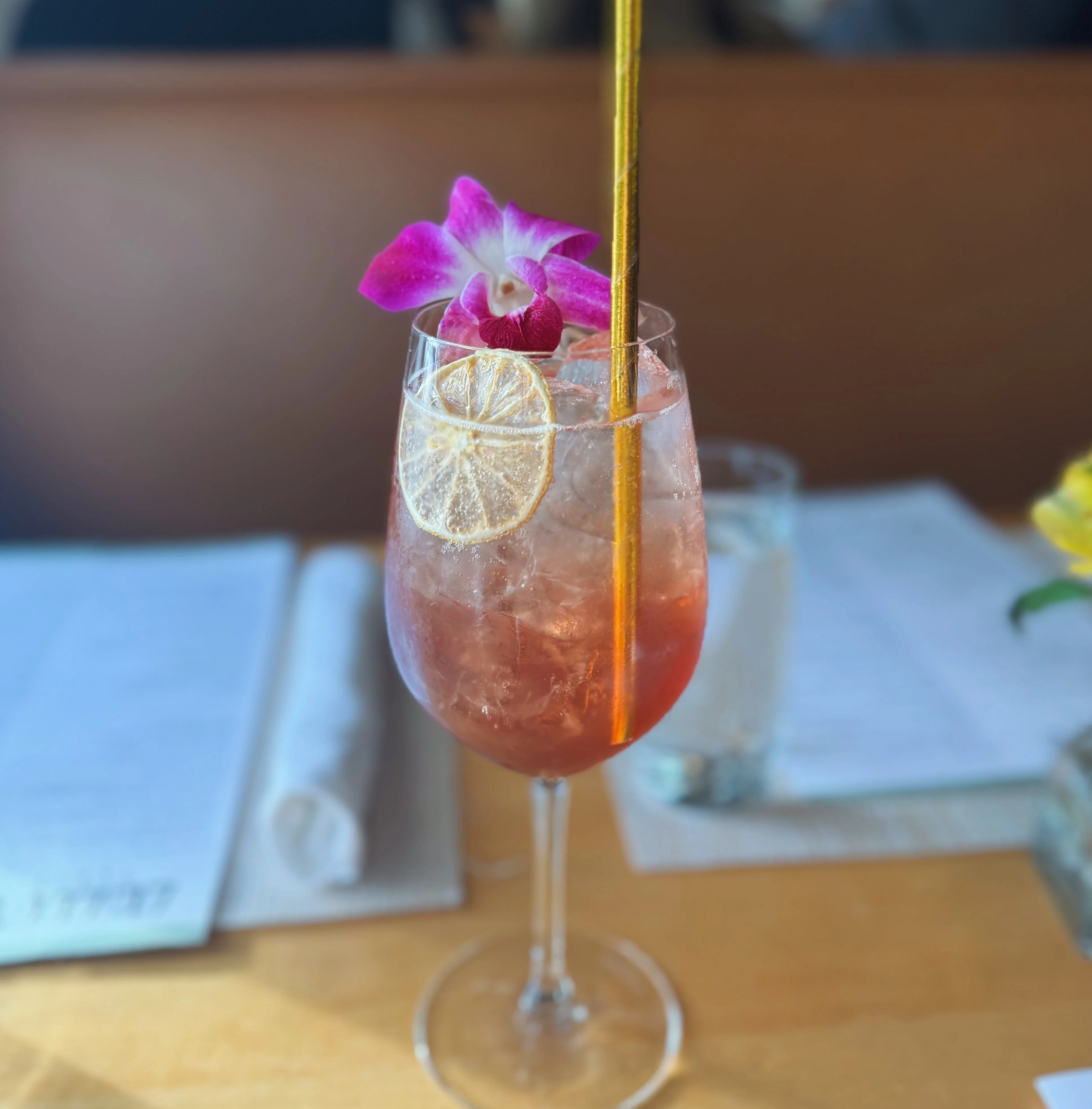 Colorful cocktail garnished with flowers and lemon slices