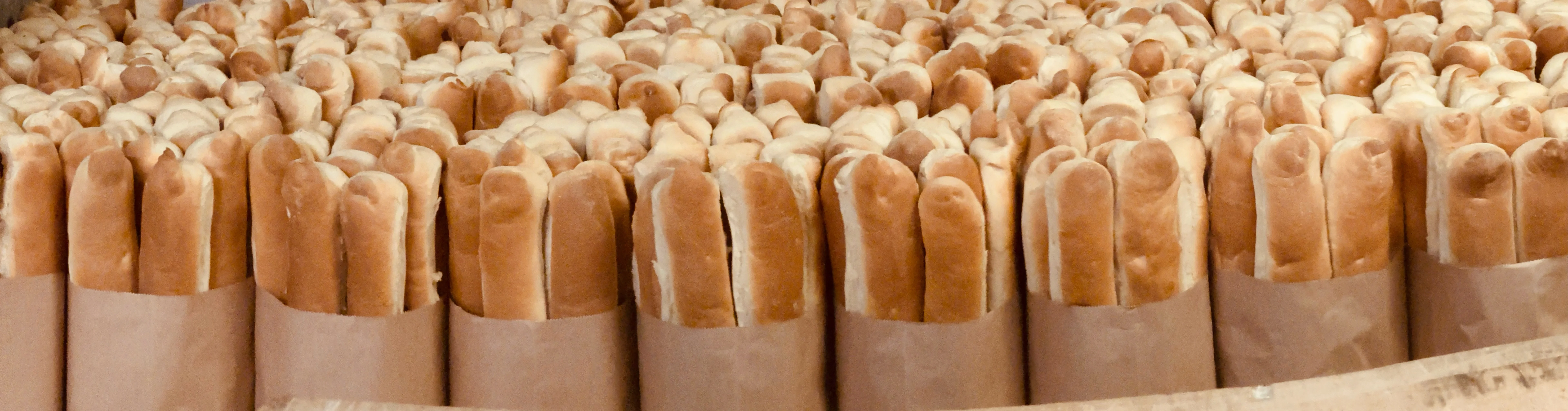 Freshly baked hot dog buns stacked in a bakery