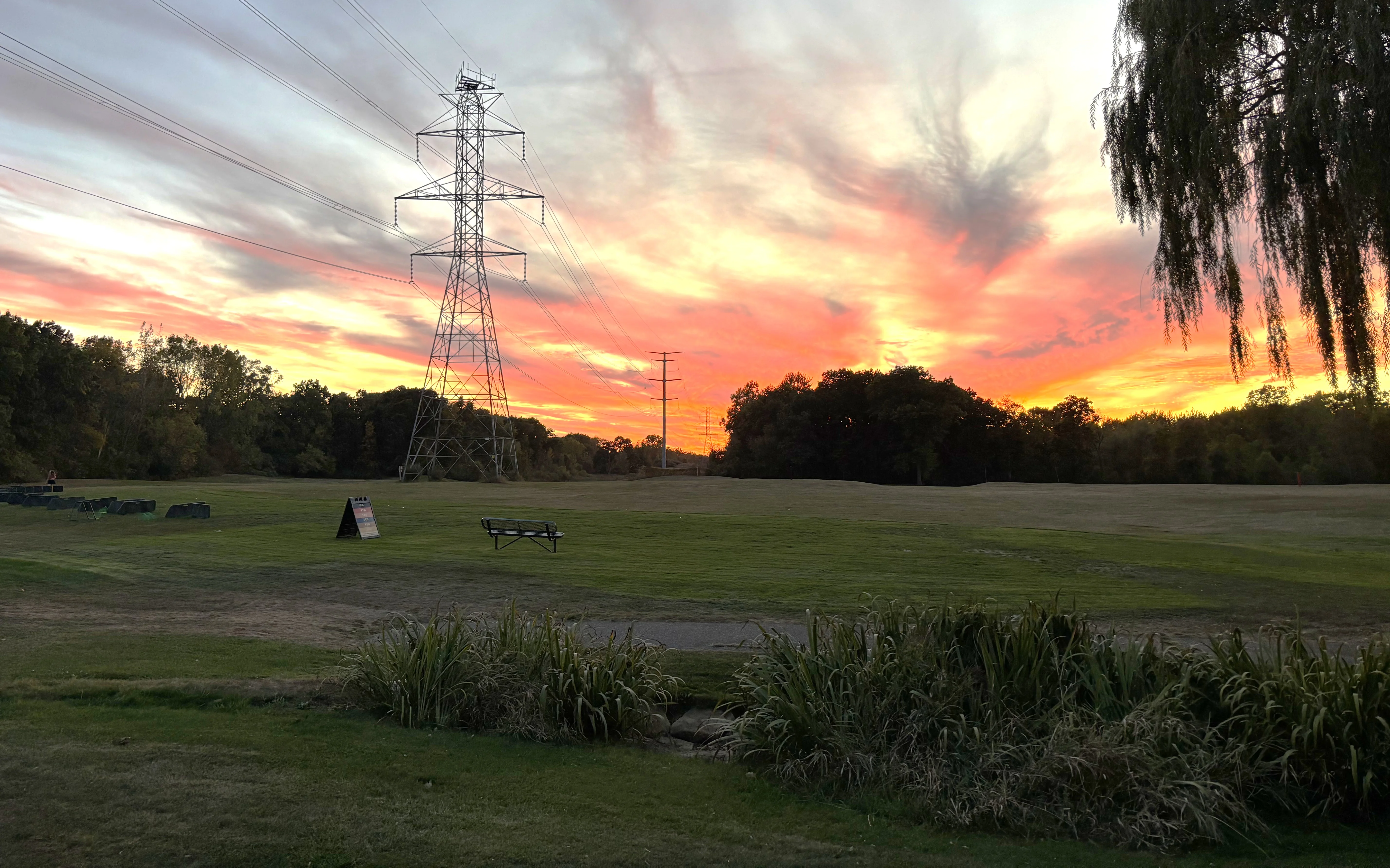 Scenic sunset over a grassy field with power lines