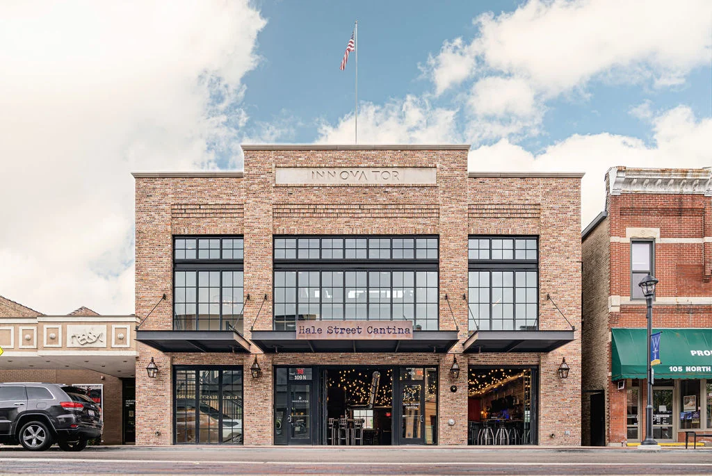 Exterior view of a modern restaurant with large windows and outdoor seating.