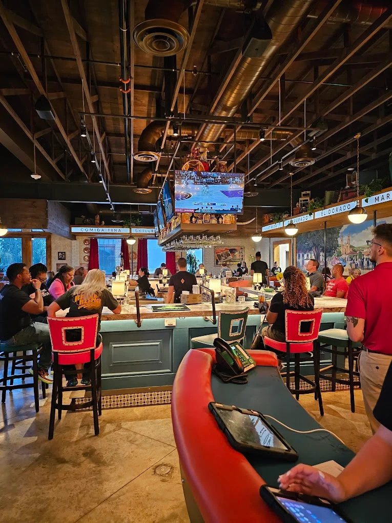 Modern bar interior with patrons enjoying drinks and sports on TV
