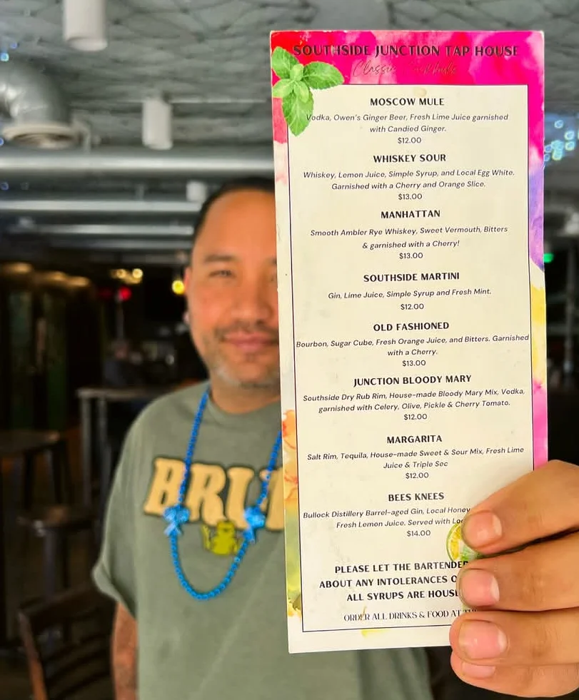Bartender showcasing cocktail menu at a vibrant bar