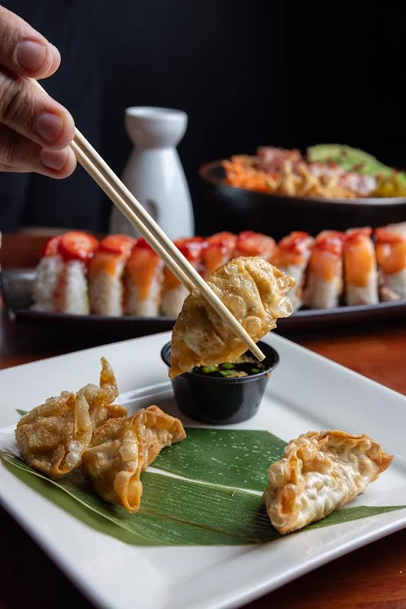 Crispy Japanese gyoza served with dipping sauce on a banana leaf