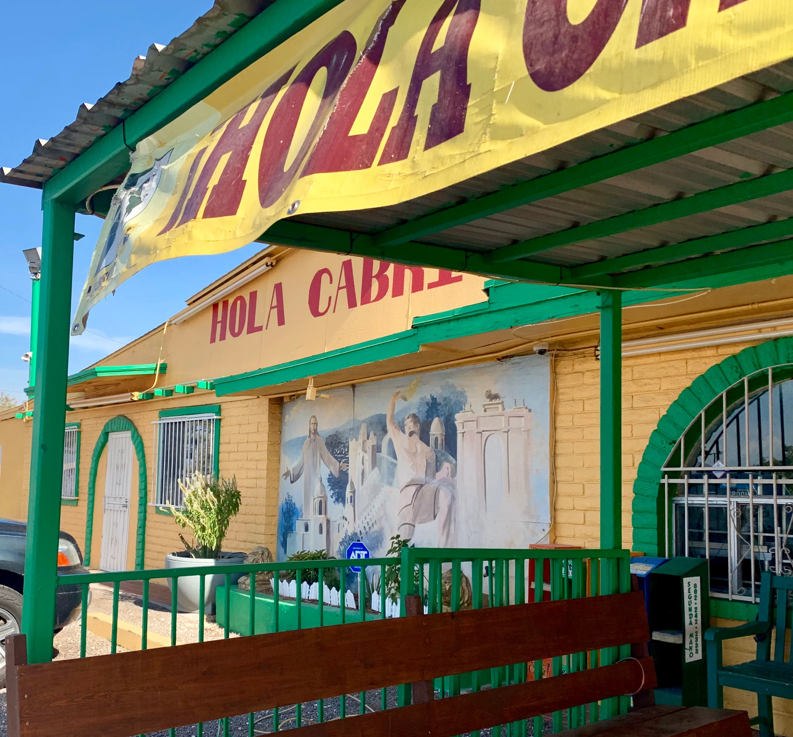 Colorful exterior of Hola Cabrita restaurant with mural and seating area