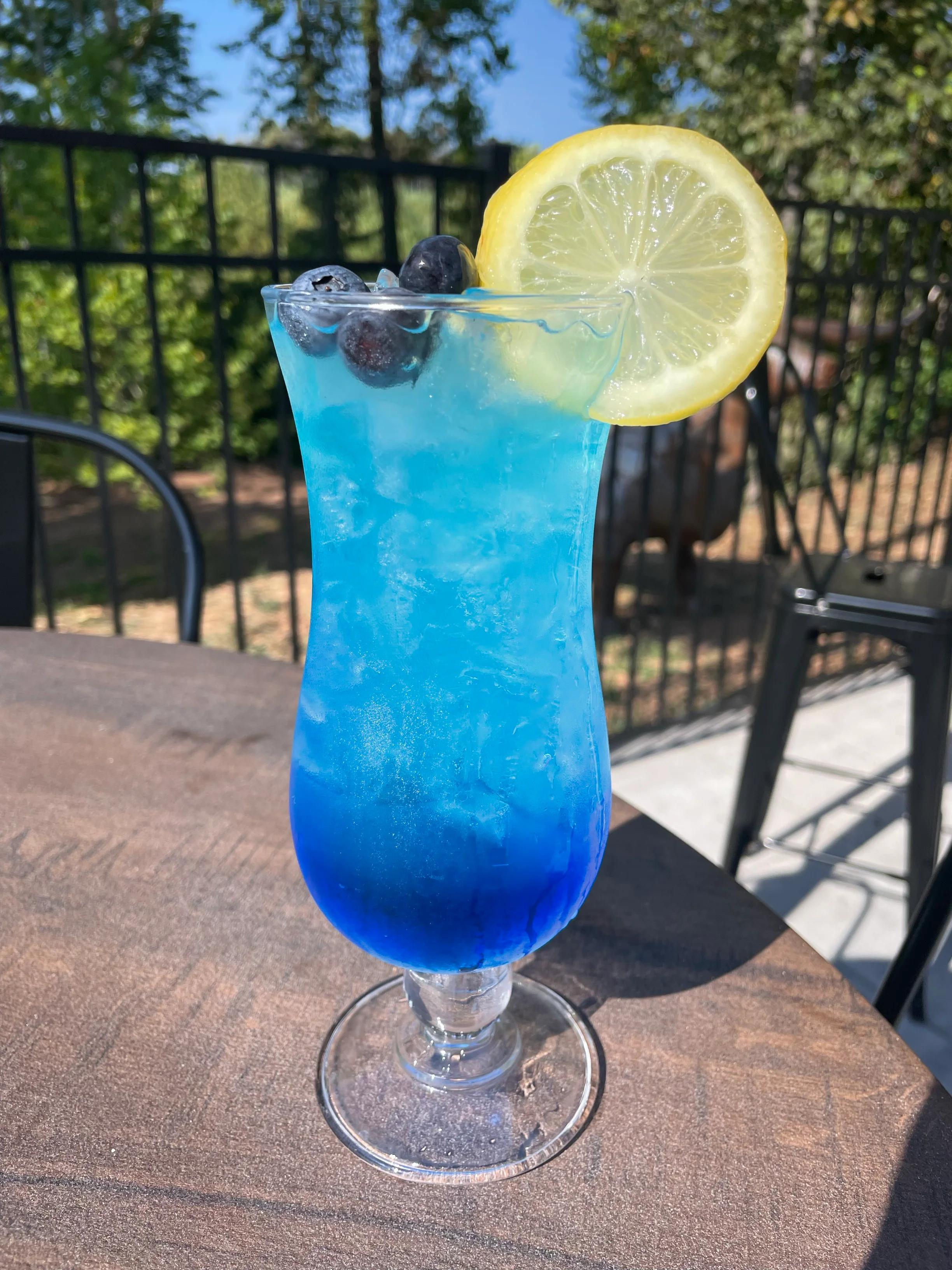 Vibrant blue cocktail garnished with lemon and blueberries