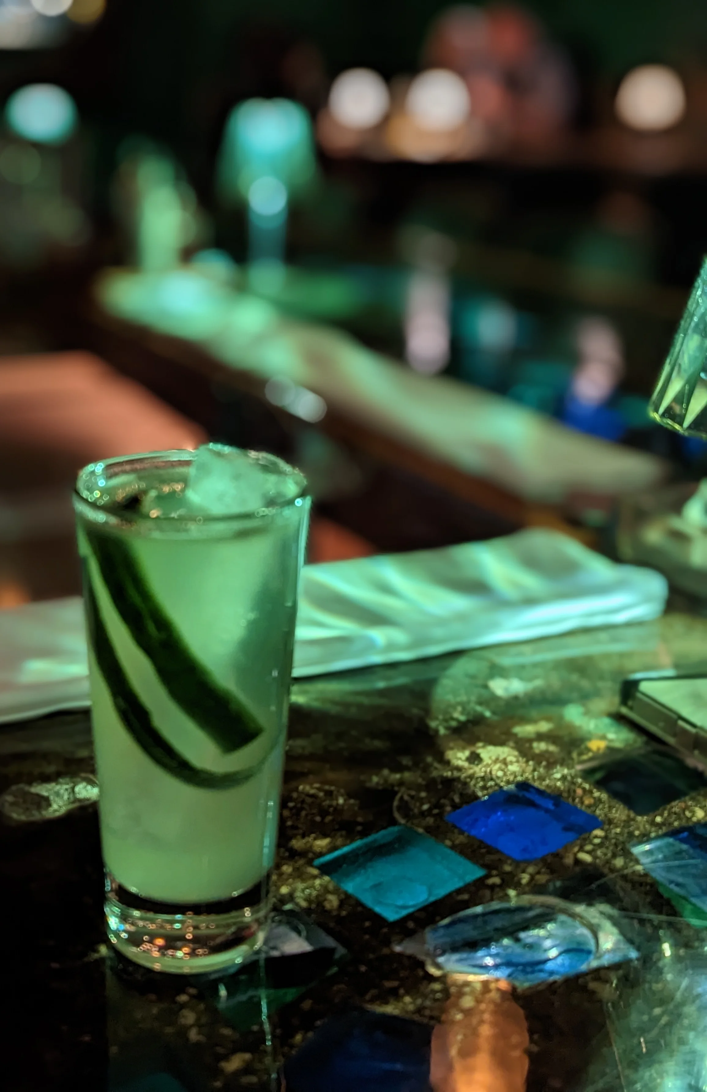 Refreshing cocktail with cucumber garnish at a stylish bar
