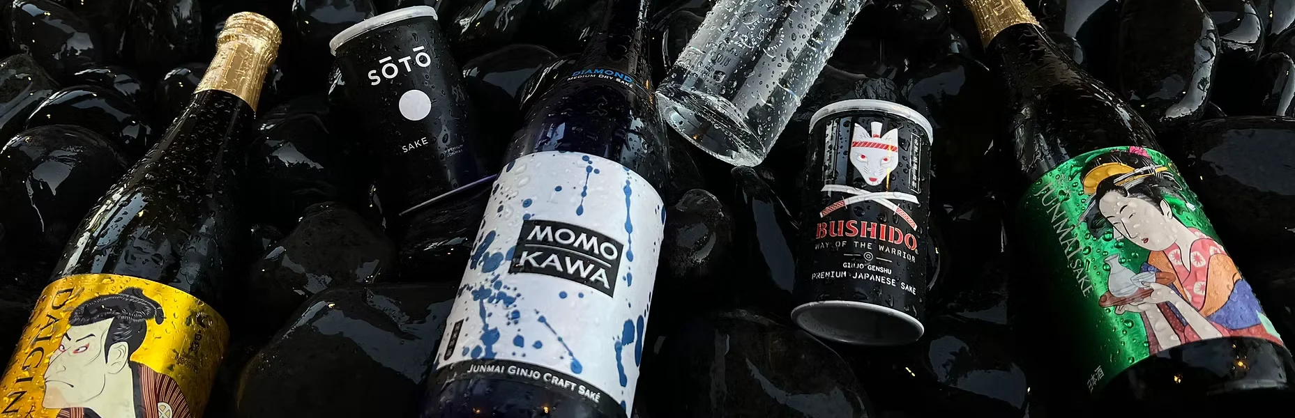 Variety of Japanese sake bottles on a bed of black stones