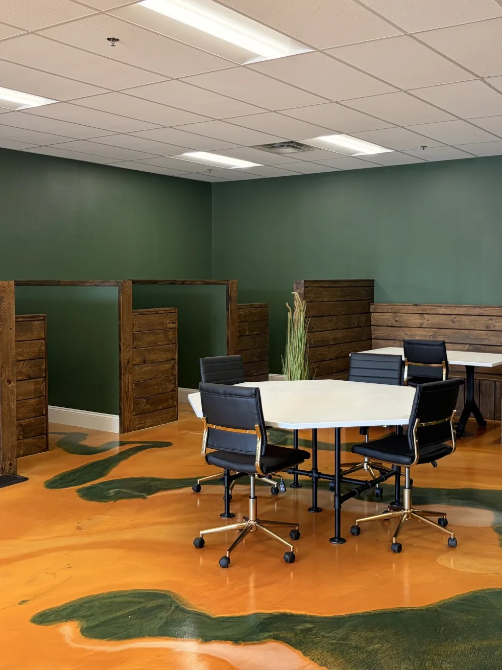 A large wooden conference table surrounded by black rolling chairs in a modern meeting room.